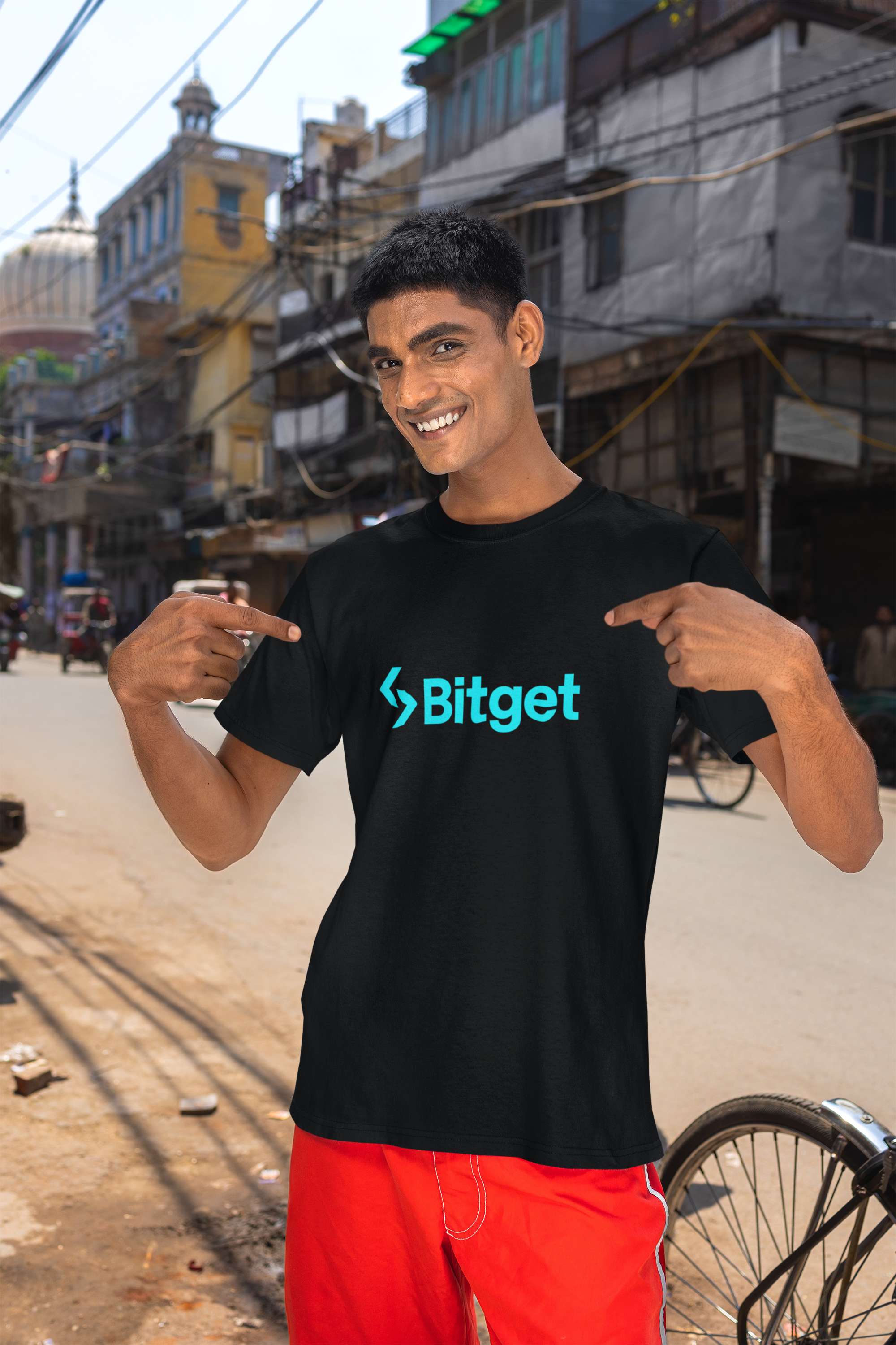 Person wearing a black t-shirt with Bitget logo in an urban setting