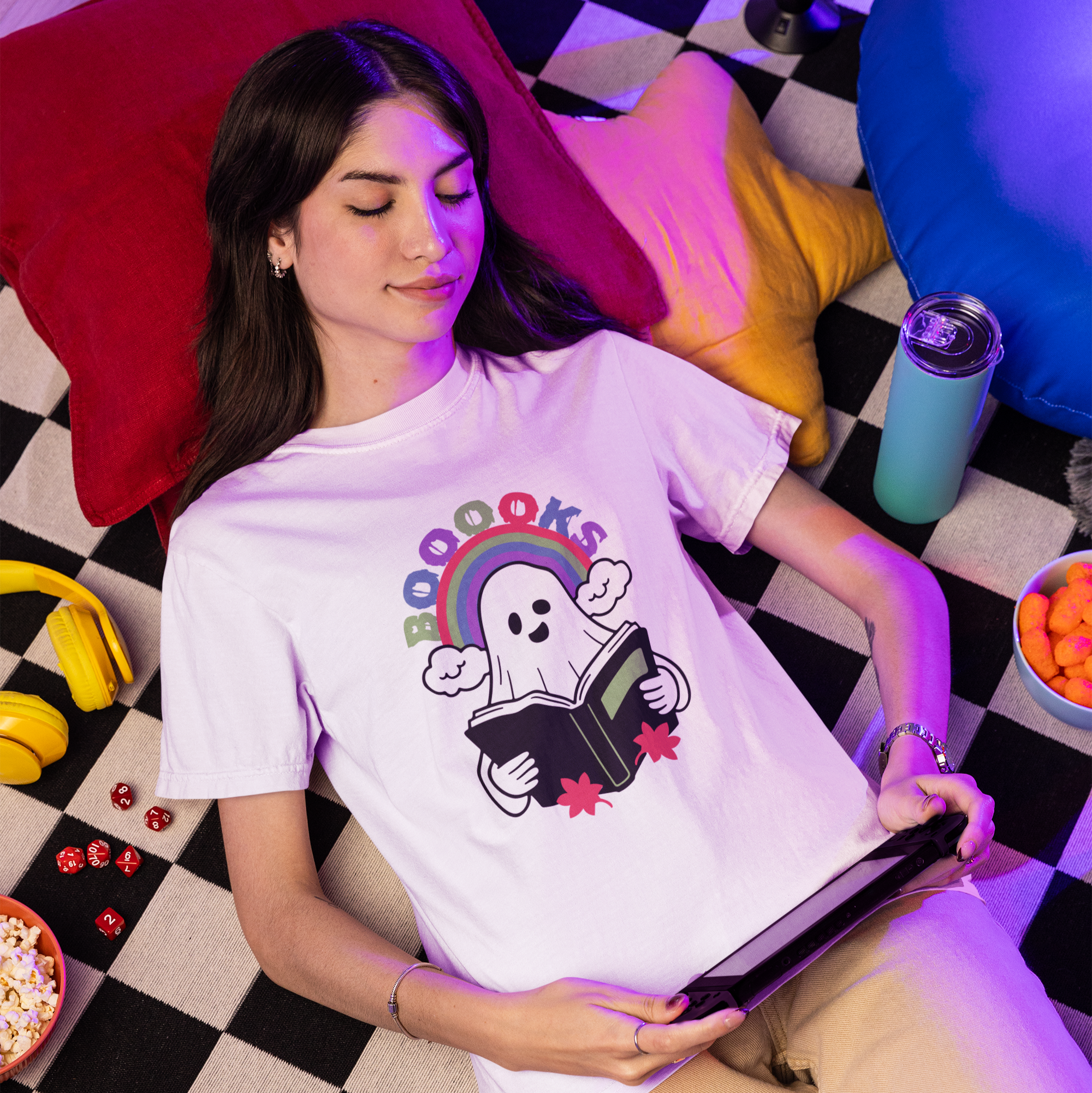 Woman wearing a t-shirt with a ghost reading a book design, lying on a checkered floor.