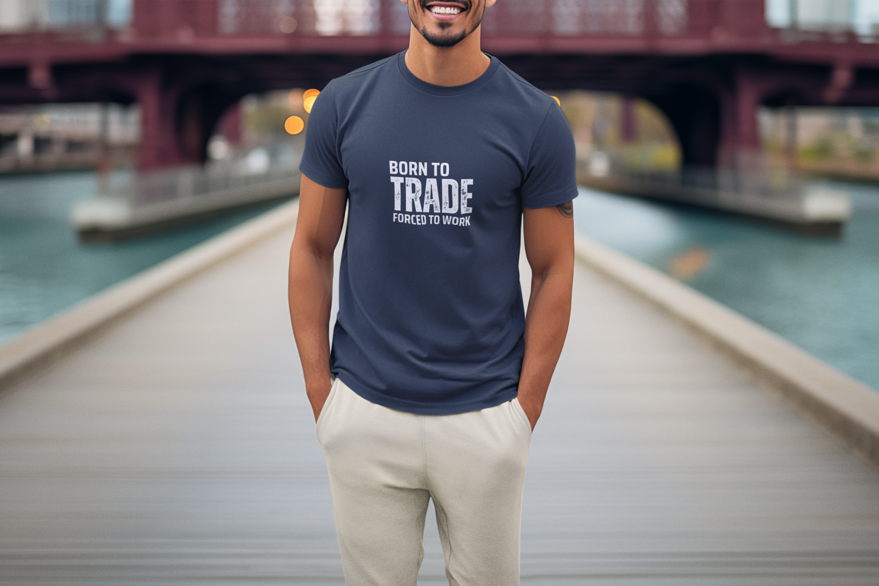 Man wearing a navy blue t-shirt with text standing on a dock with a bridge in the background