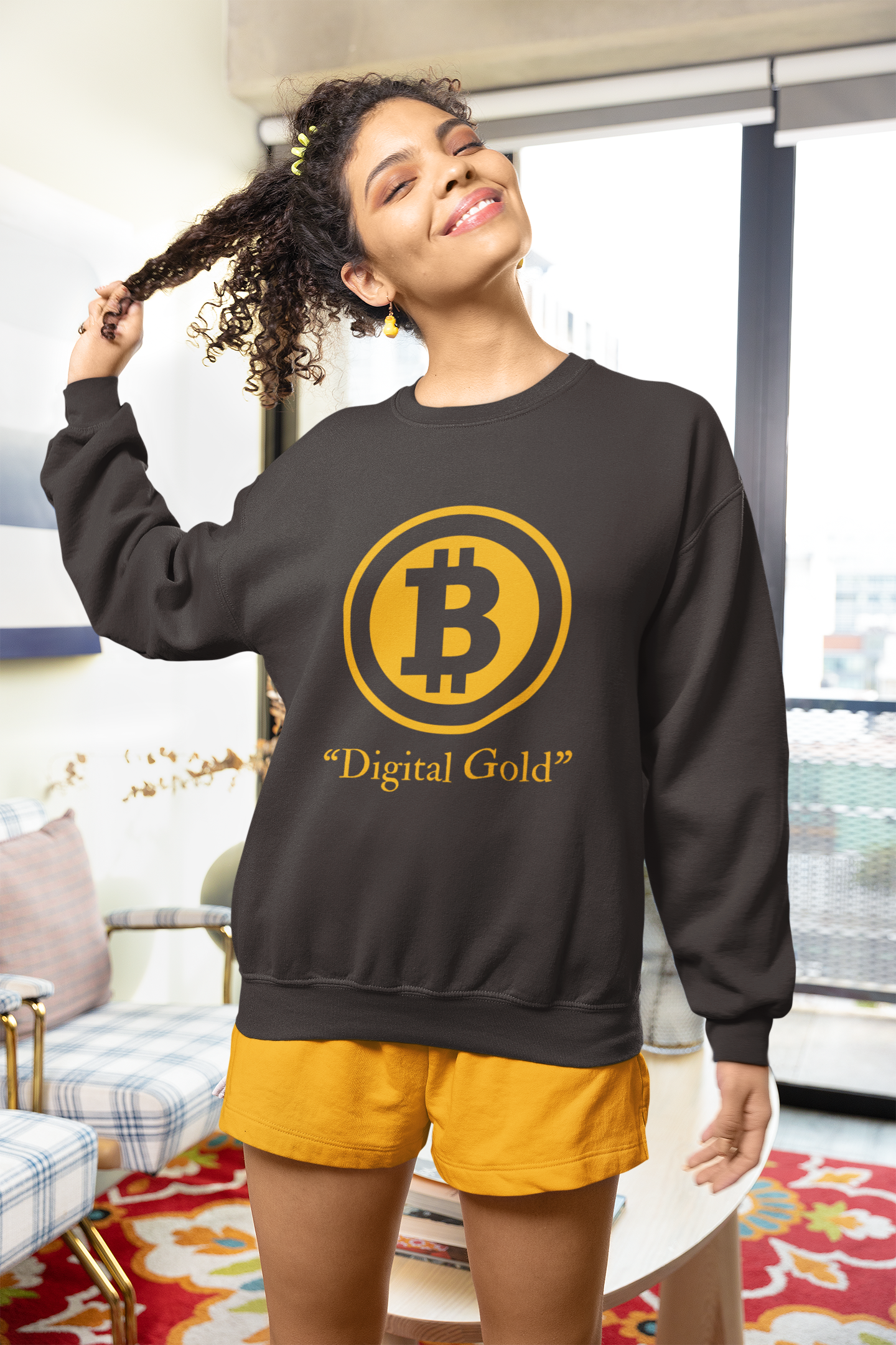 Woman wearing a black sweatshirt with a Bitcoin symbol and 'Digital Gold' text in a living room.