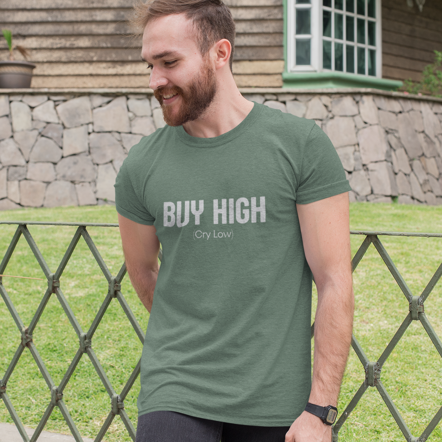 Man wearing a green t-shirt with 'BUY HIGH Cry Low' text outdoors.