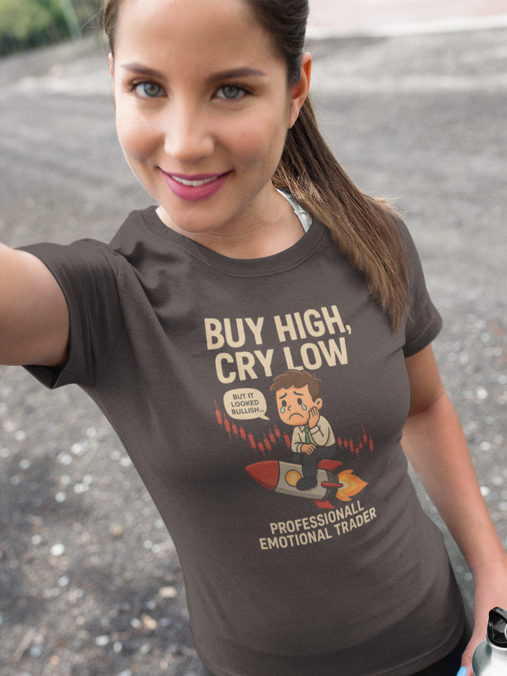 Woman wearing a brown t-shirt with a graphic and text, standing on a road.