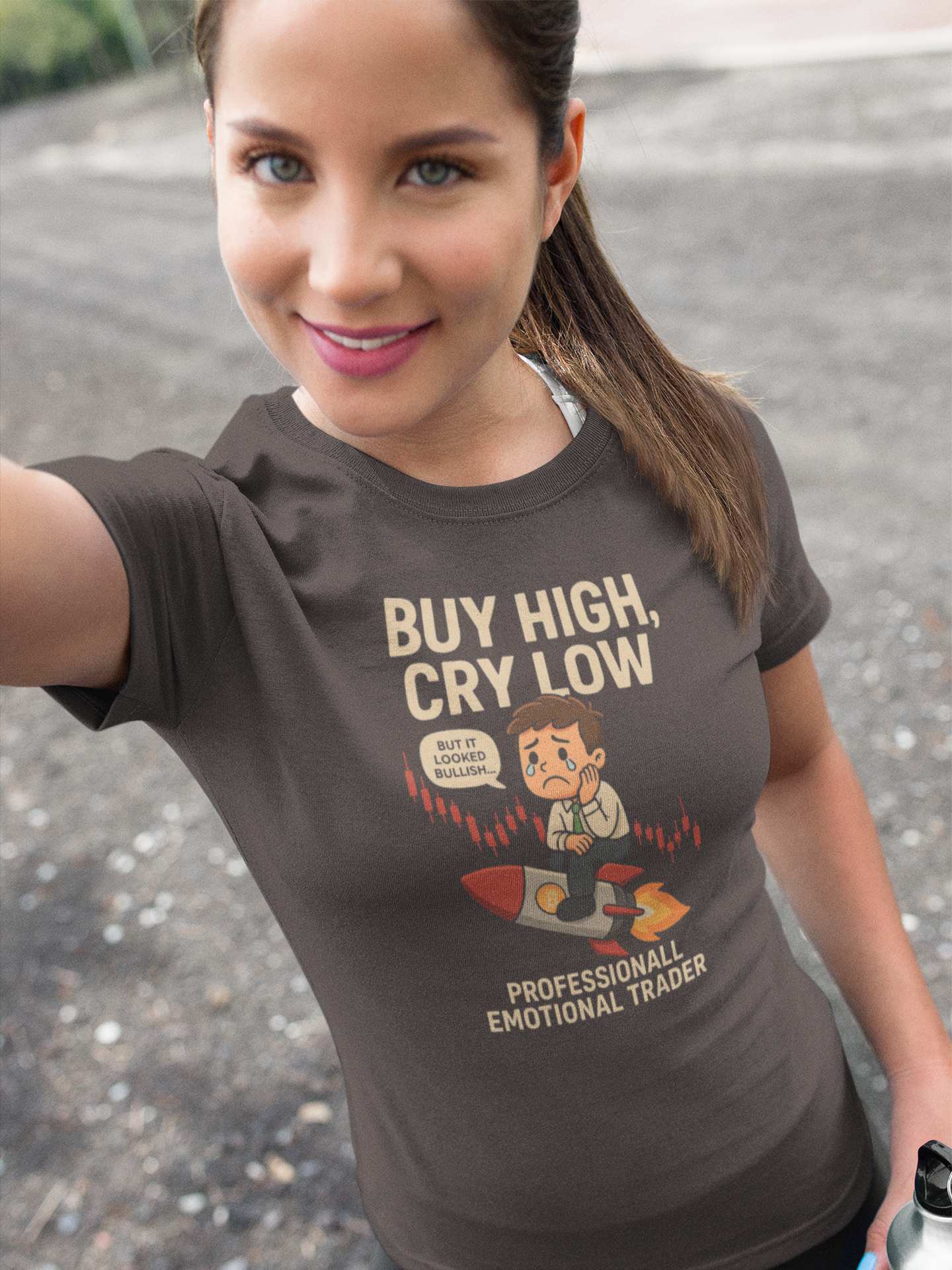 Woman wearing a brown t-shirt with a graphic and text, standing on a road.