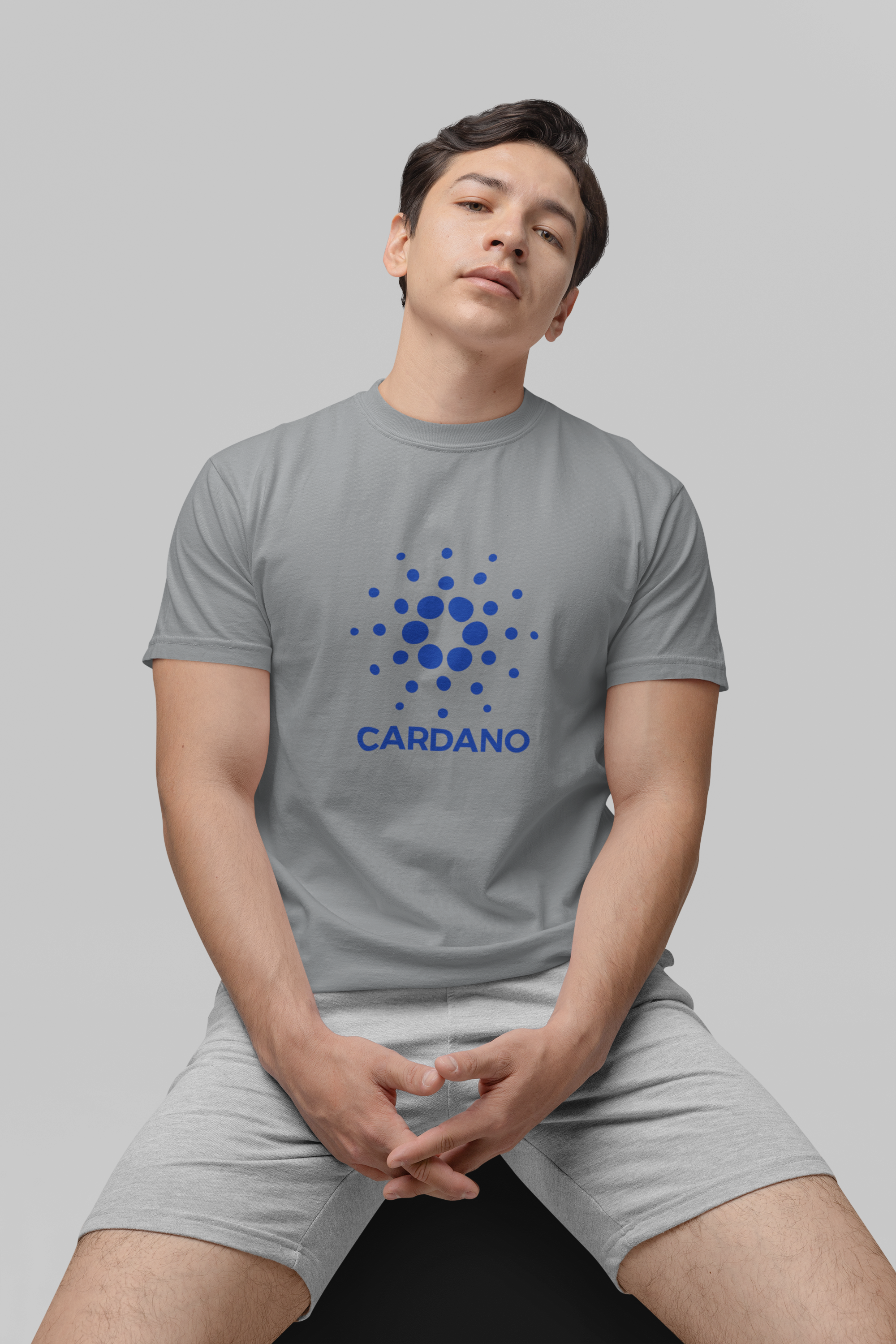 Person wearing a gray t-shirt with Cardano logo on a plain background