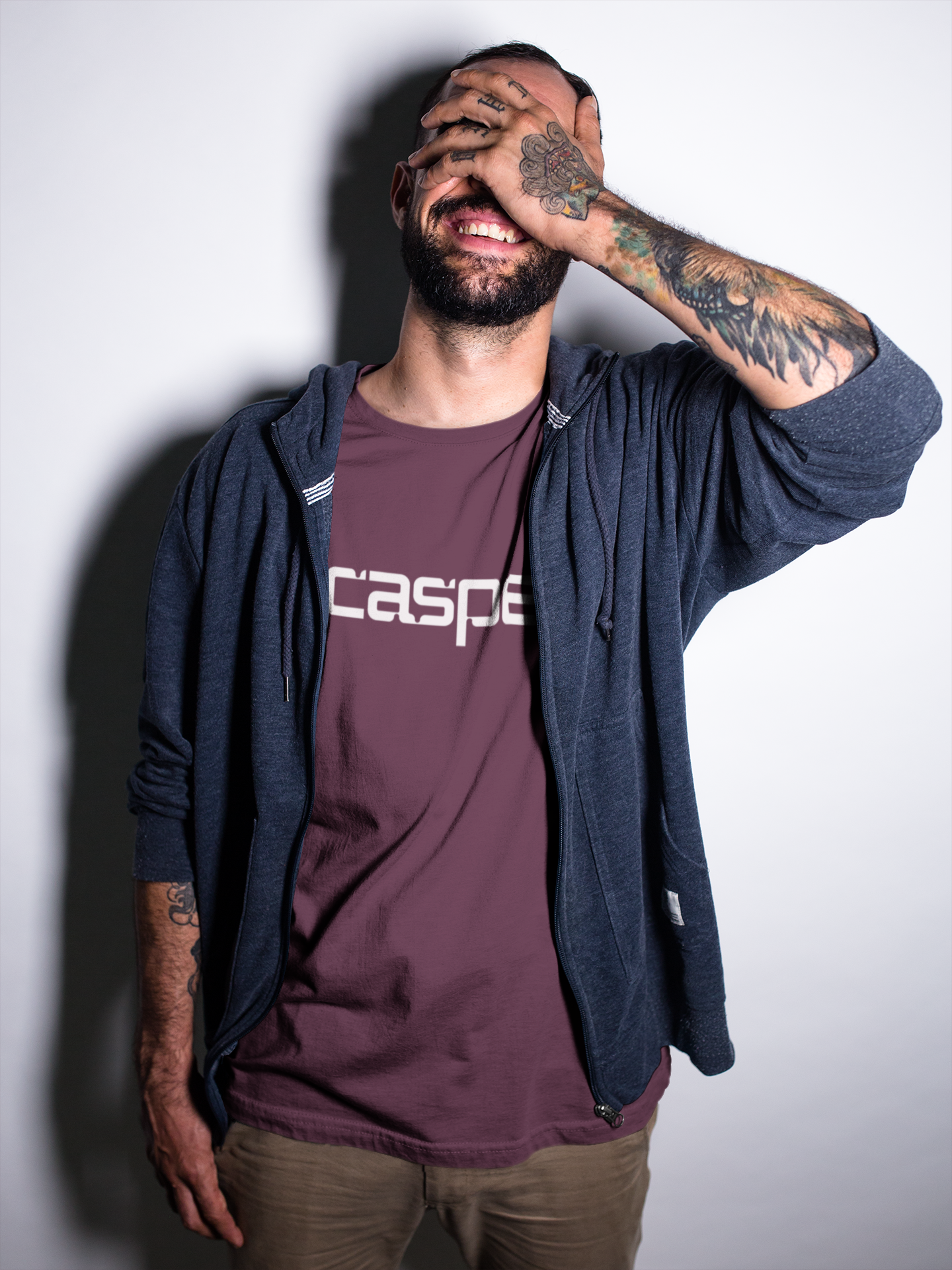 Man wearing a maroon 'casper' t-shirt with a dark blue hoodie against a plain background