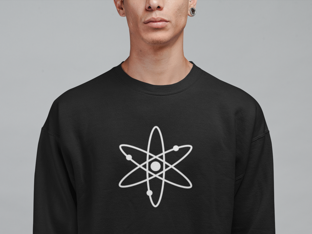 Person wearing a black sweatshirt with an atom symbol on a gray background