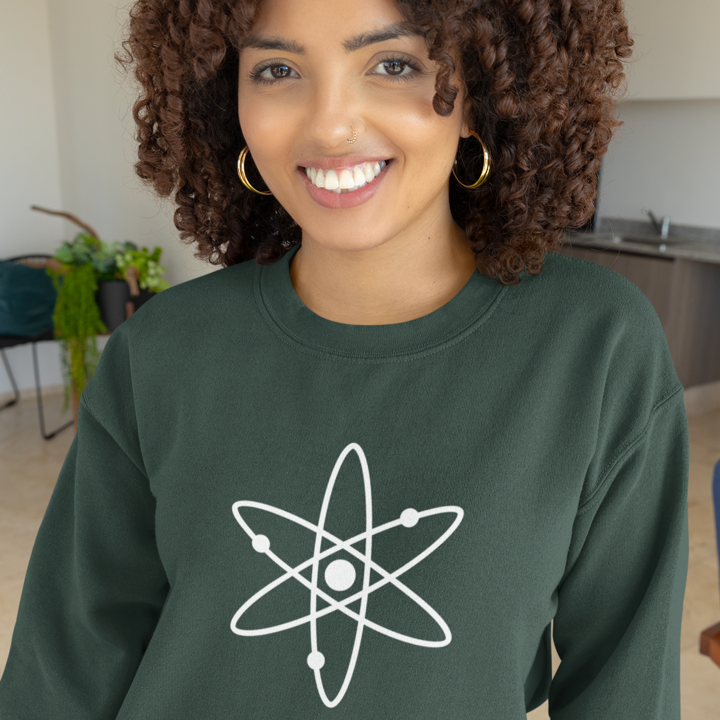 Person wearing a green sweatshirt with an atom symbol in a casual indoor setting