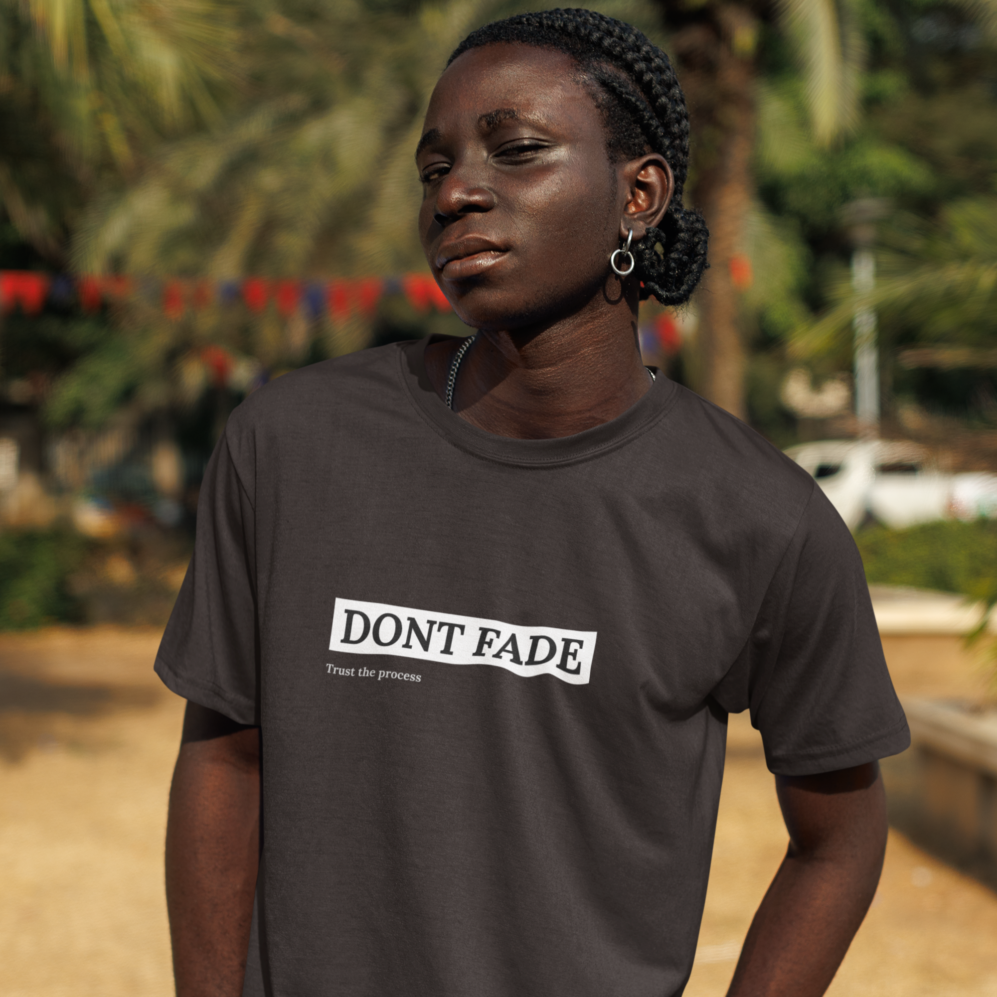 Person wearing a dark gray t-shirt with 'DON'T FADE' text, standing outdoors.