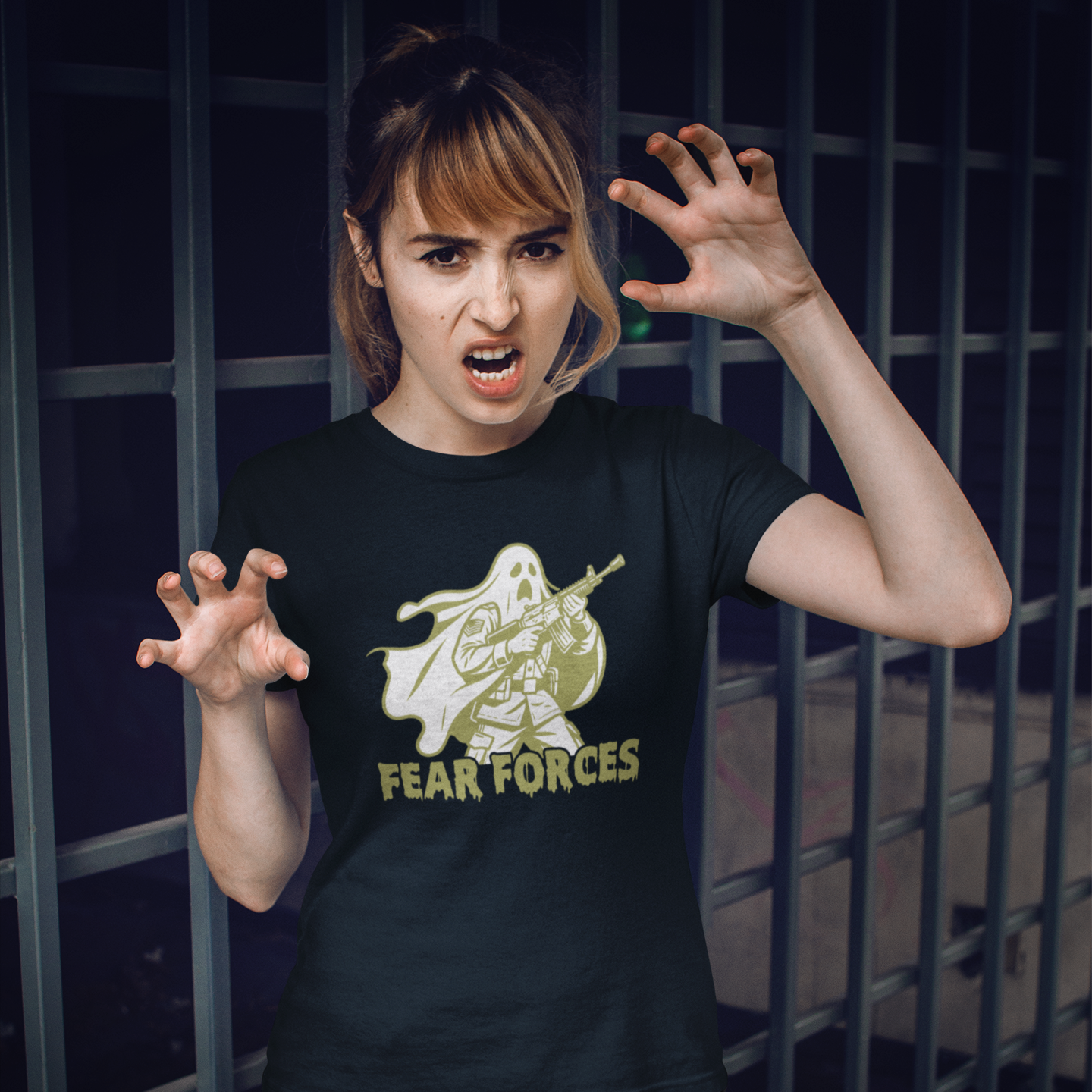 Person wearing a black t-shirt with a graphic design and text, standing in front of a metal fence.