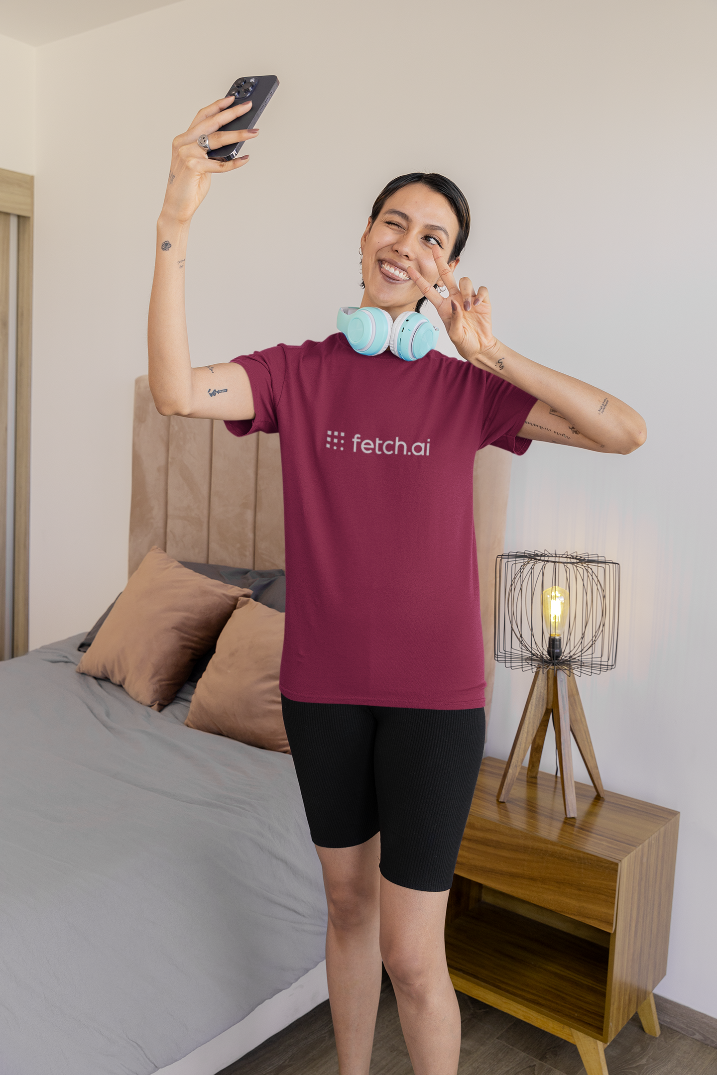 Person wearing a maroon 'fetch.ai' shirt in a bedroom setting