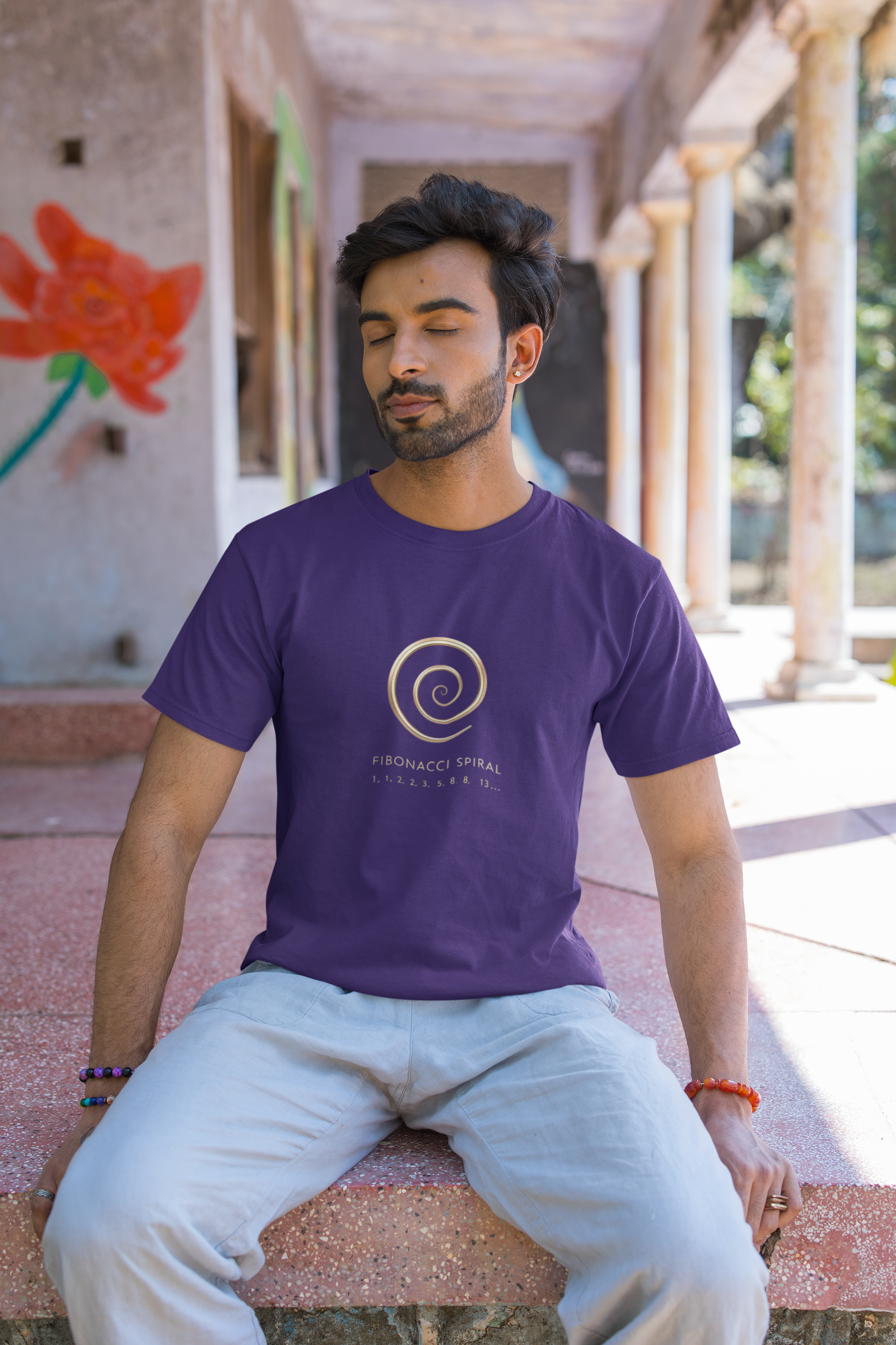 Man wearing a purple t-shirt with a logo sitting outdoors.