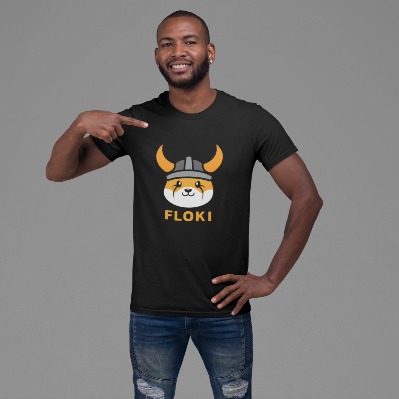 Man pointing to a black t-shirt with a 'FLOKI' design on a gray background