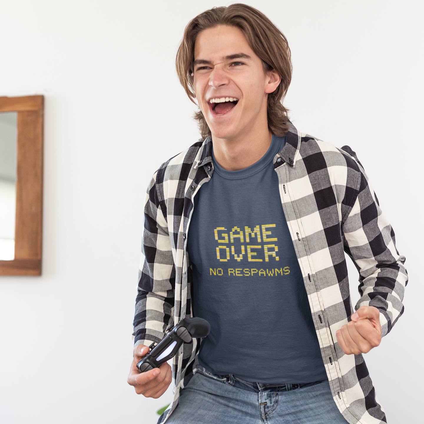 Man wearing a 'Game Over No Respins' t-shirt, sitting on a couch with a gaming console.