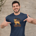 Man pointing to a navy blue t-shirt with a dog graphic and text against a concrete wall.
