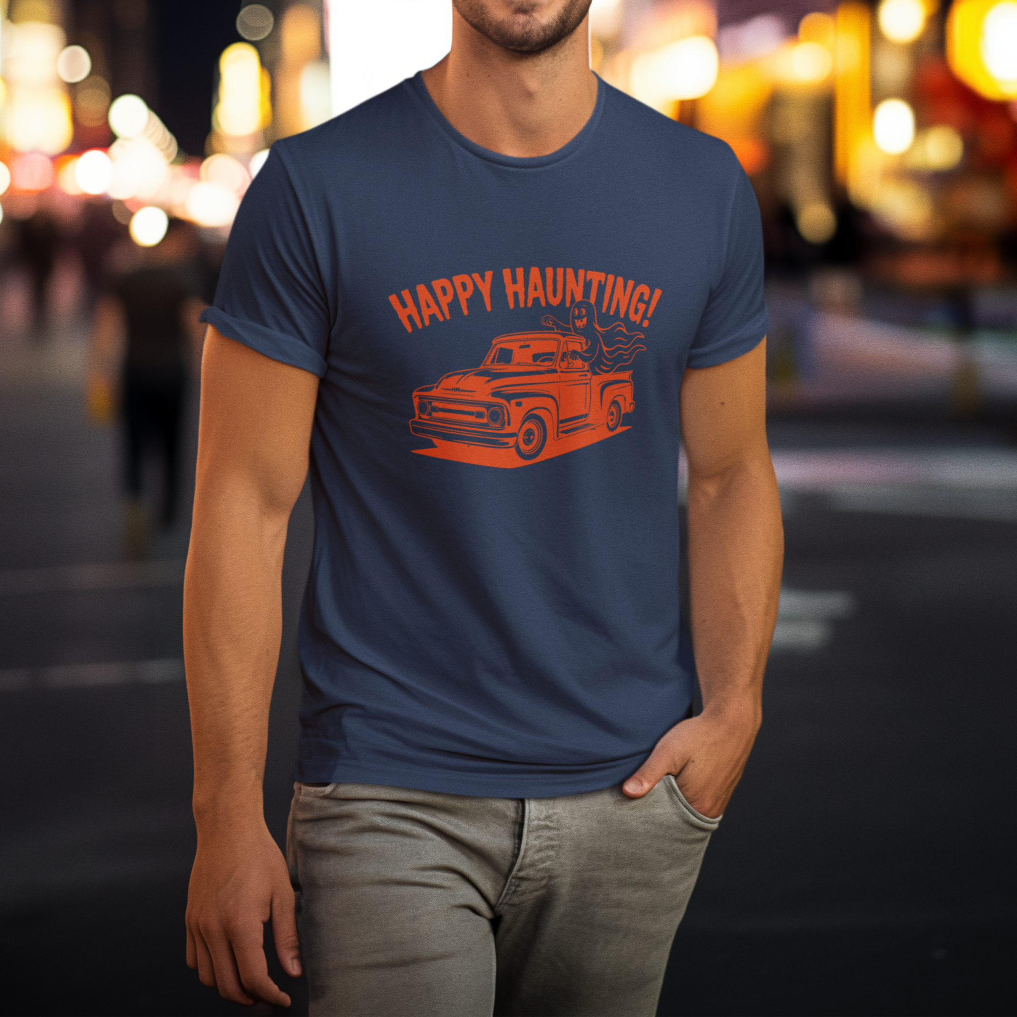 Person wearing a blue t-shirt with 'Happy Haunting!' design on a city street at night.