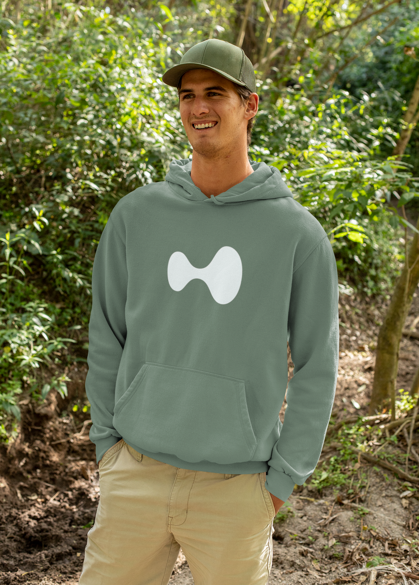 Man wearing a green hoodie with a white logo in a forest setting