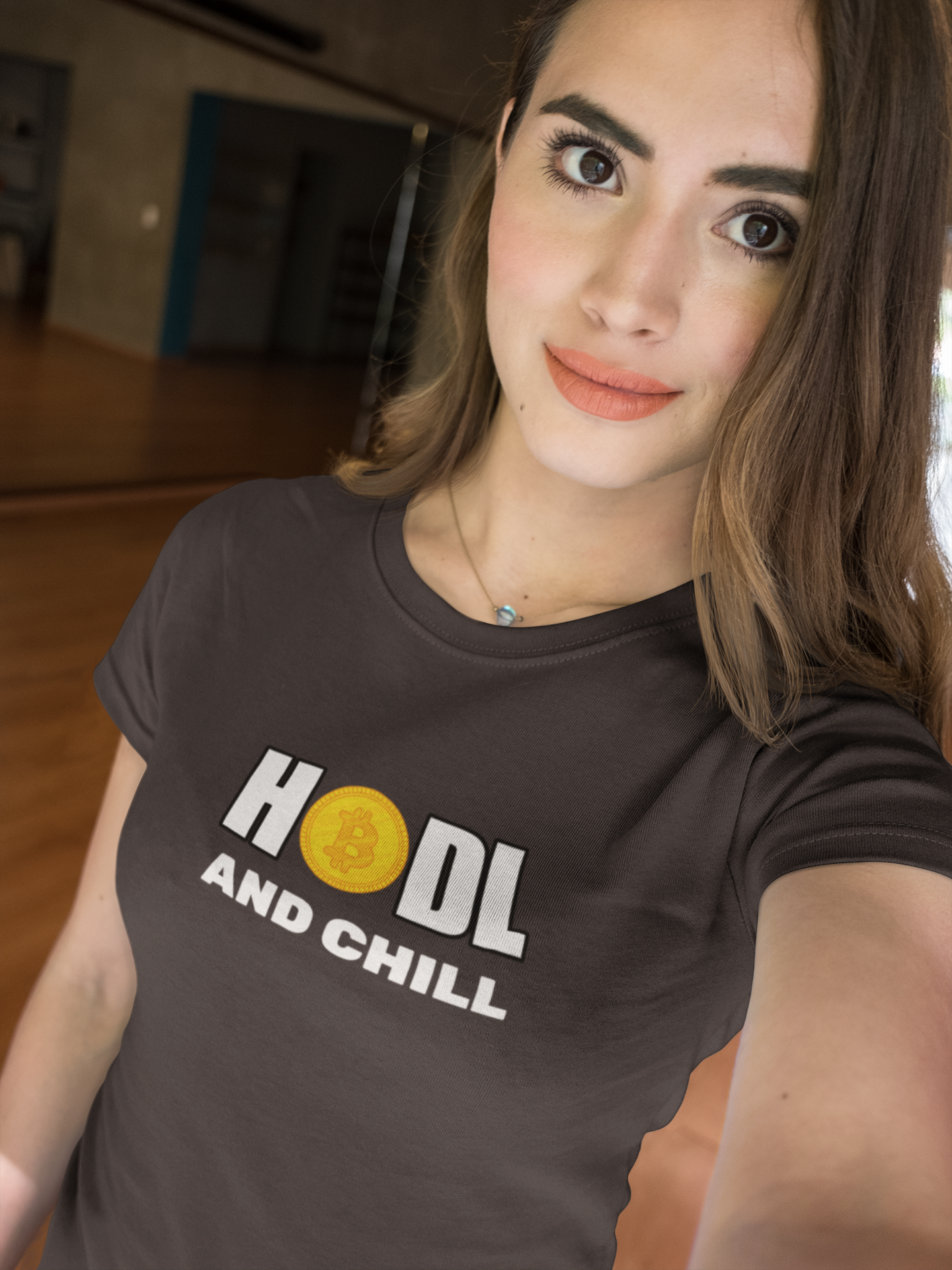 Woman wearing a brown t-shirt with 'HODL AND CHILL' text and a coin graphic.