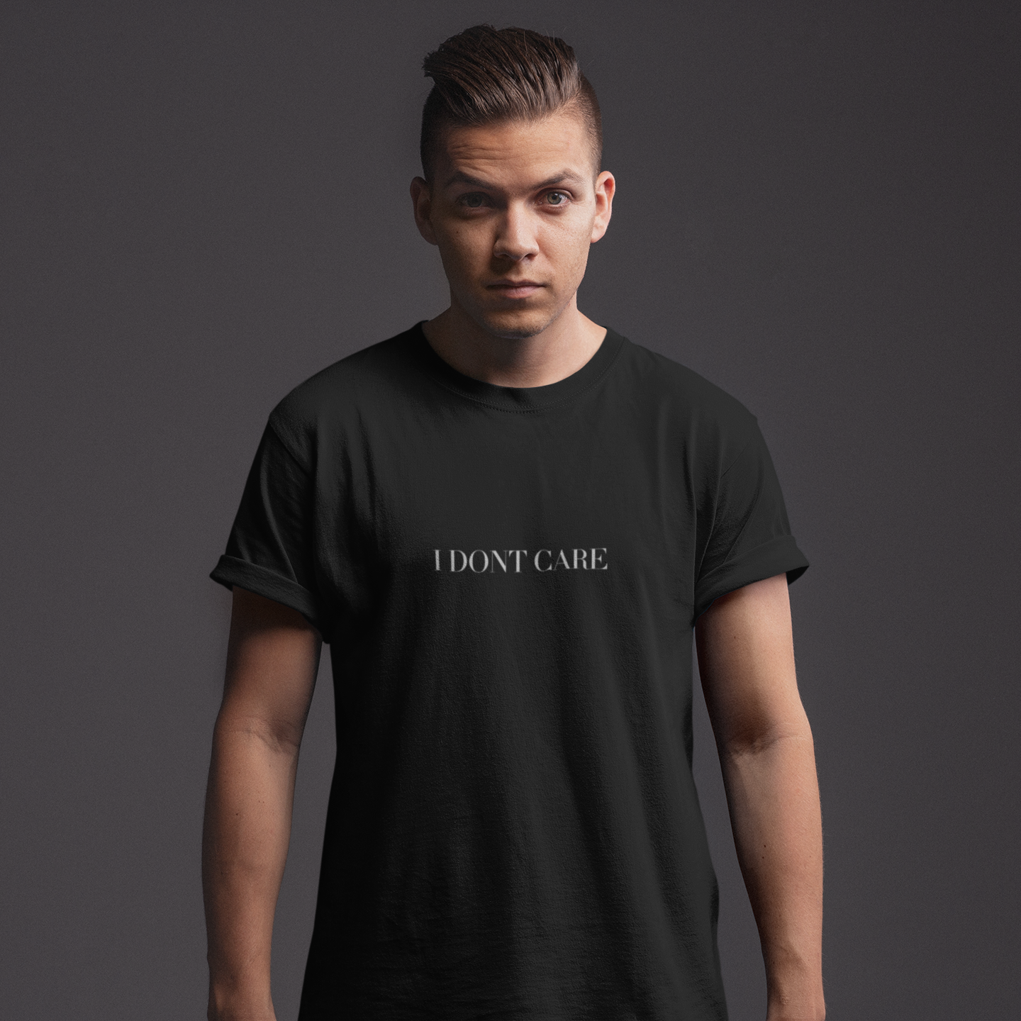 Person wearing a black t-shirt with 'I DON'T CARE' text on a dark background