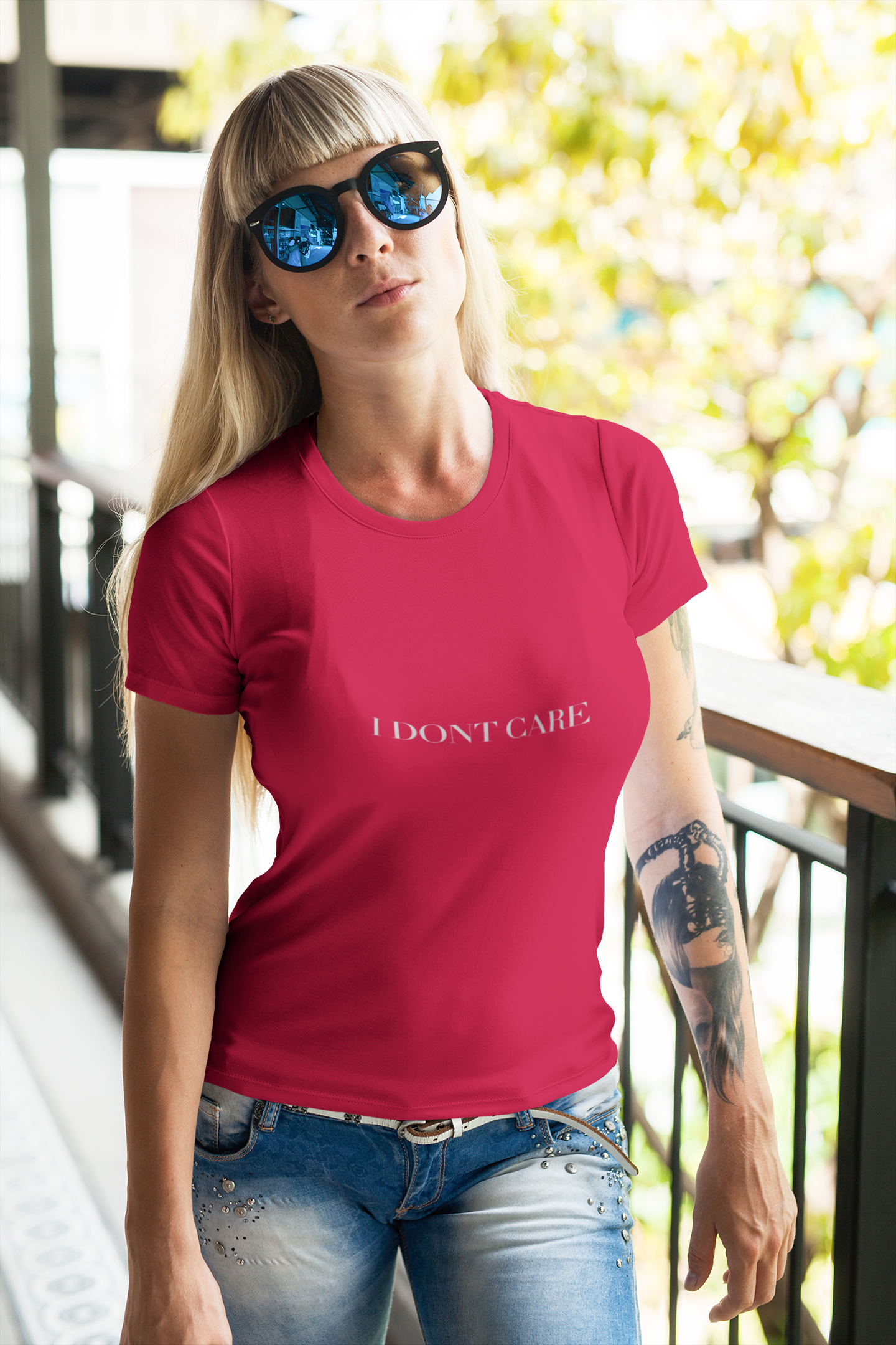 Woman wearing a red t-shirt with 'I DON'T CARE' text, standing outdoors.
