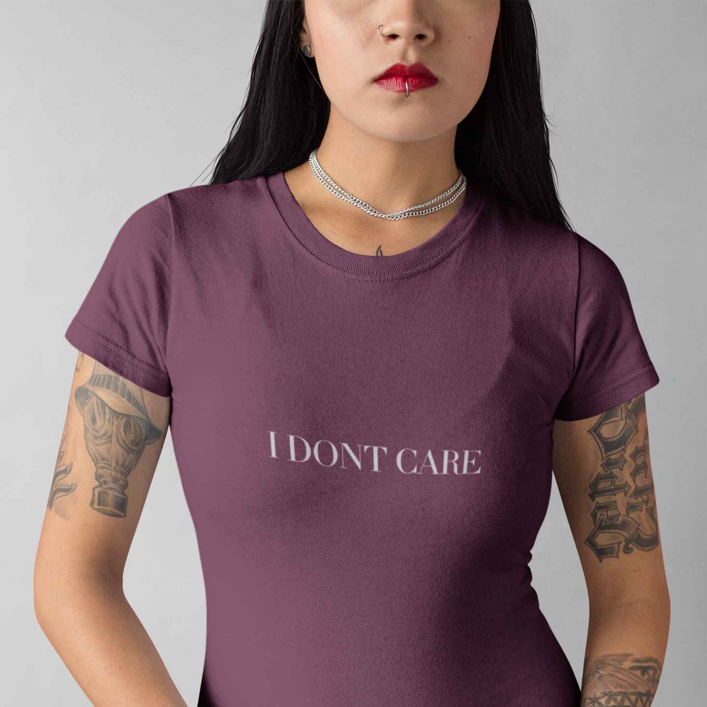 Person wearing a maroon t-shirt with 'I DON'T CARE' text on a gray background