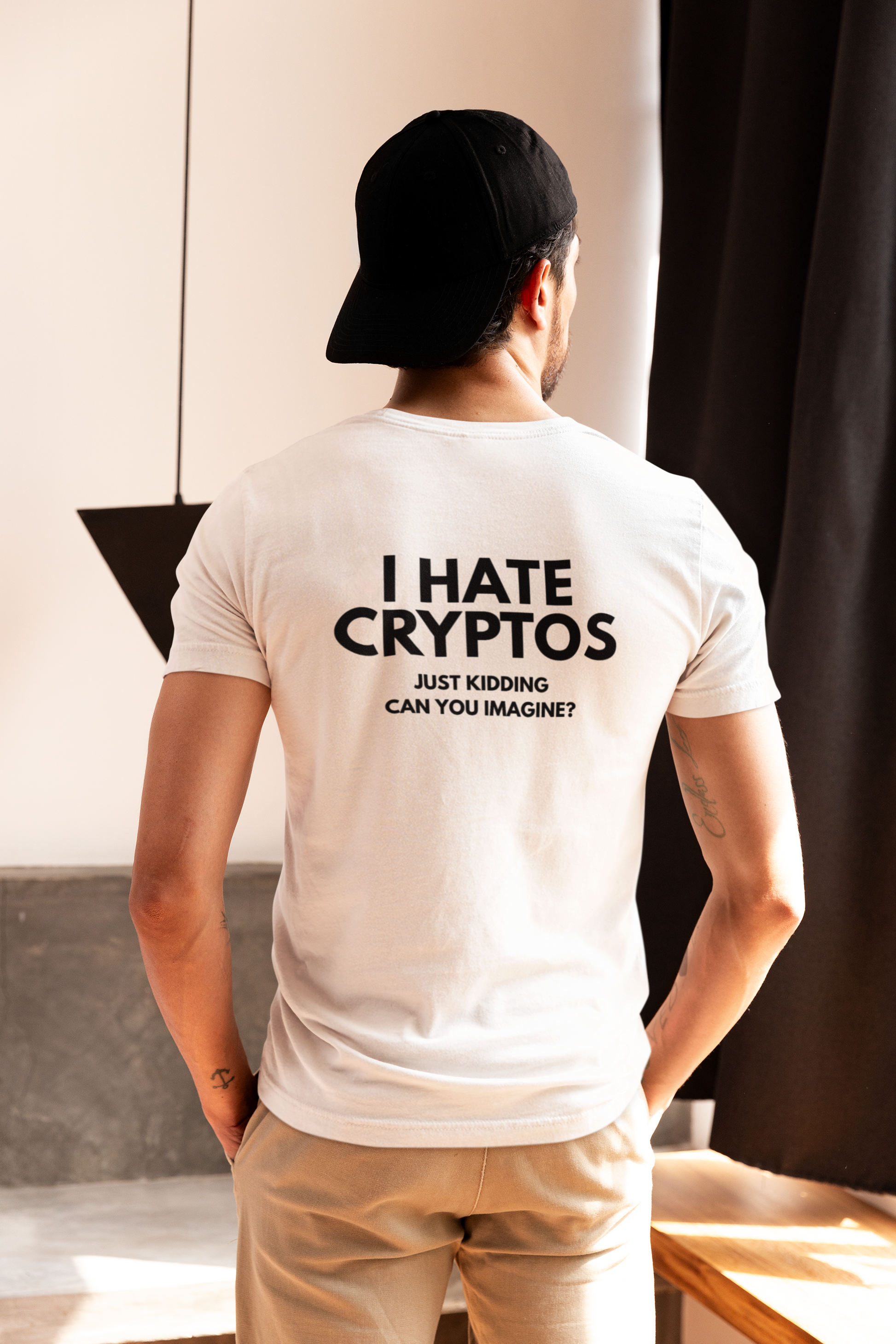 Person wearing a white t-shirt with humorous text on the back, standing indoors.