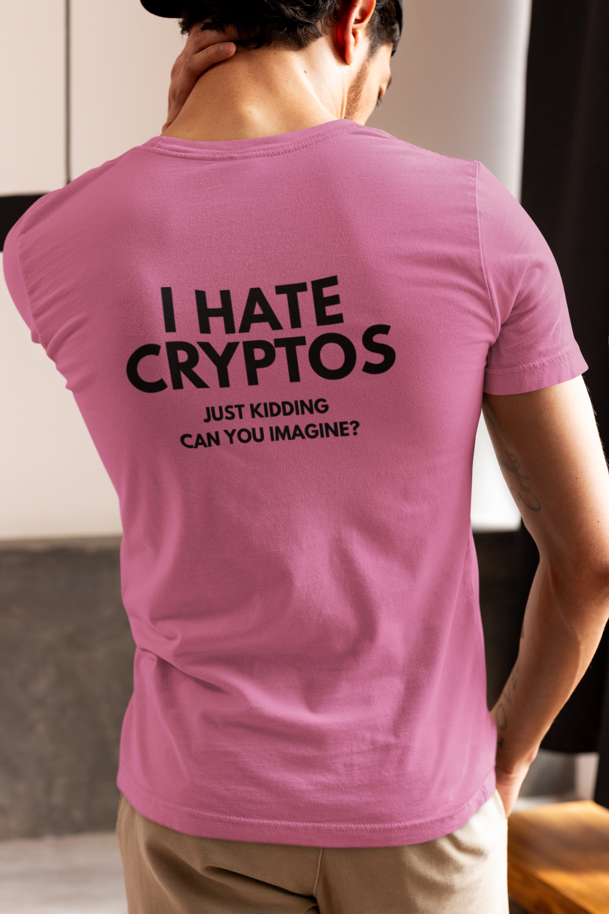 Person wearing a pink t-shirt with text on the back, standing indoors.