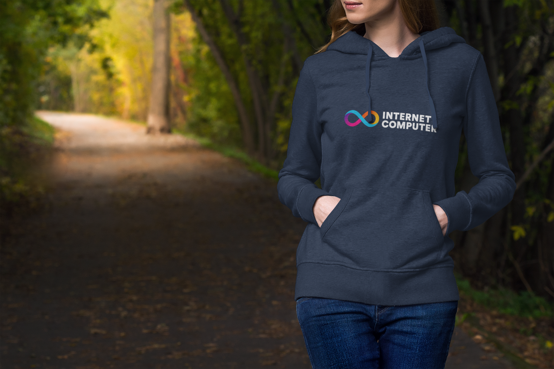 Person wearing a navy hoodie with 'Internet Computer' logo in a forest setting