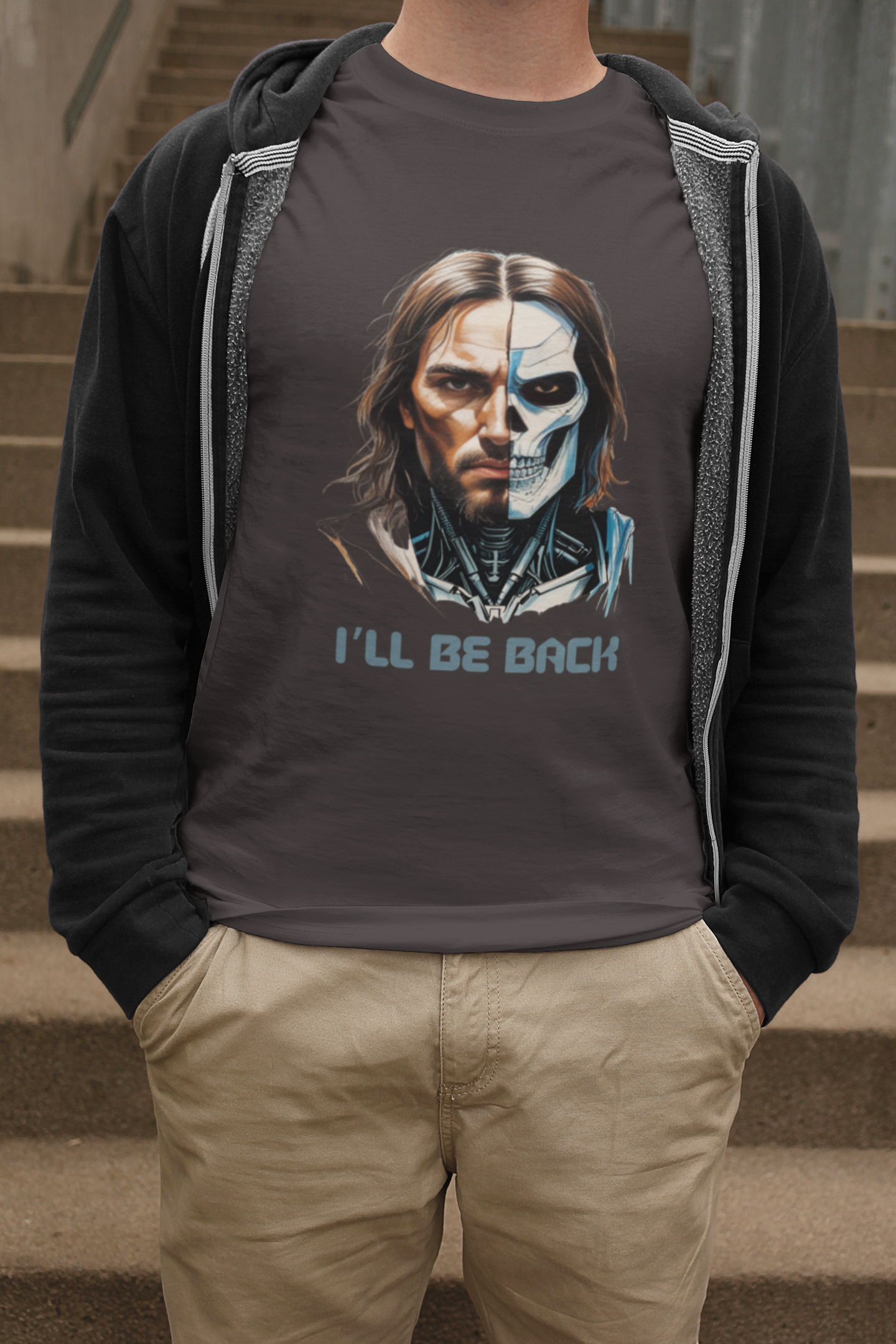 Person wearing a hoodie with a graphic design of a face split into two halves and text 'I'll Be Back' on a gray background.