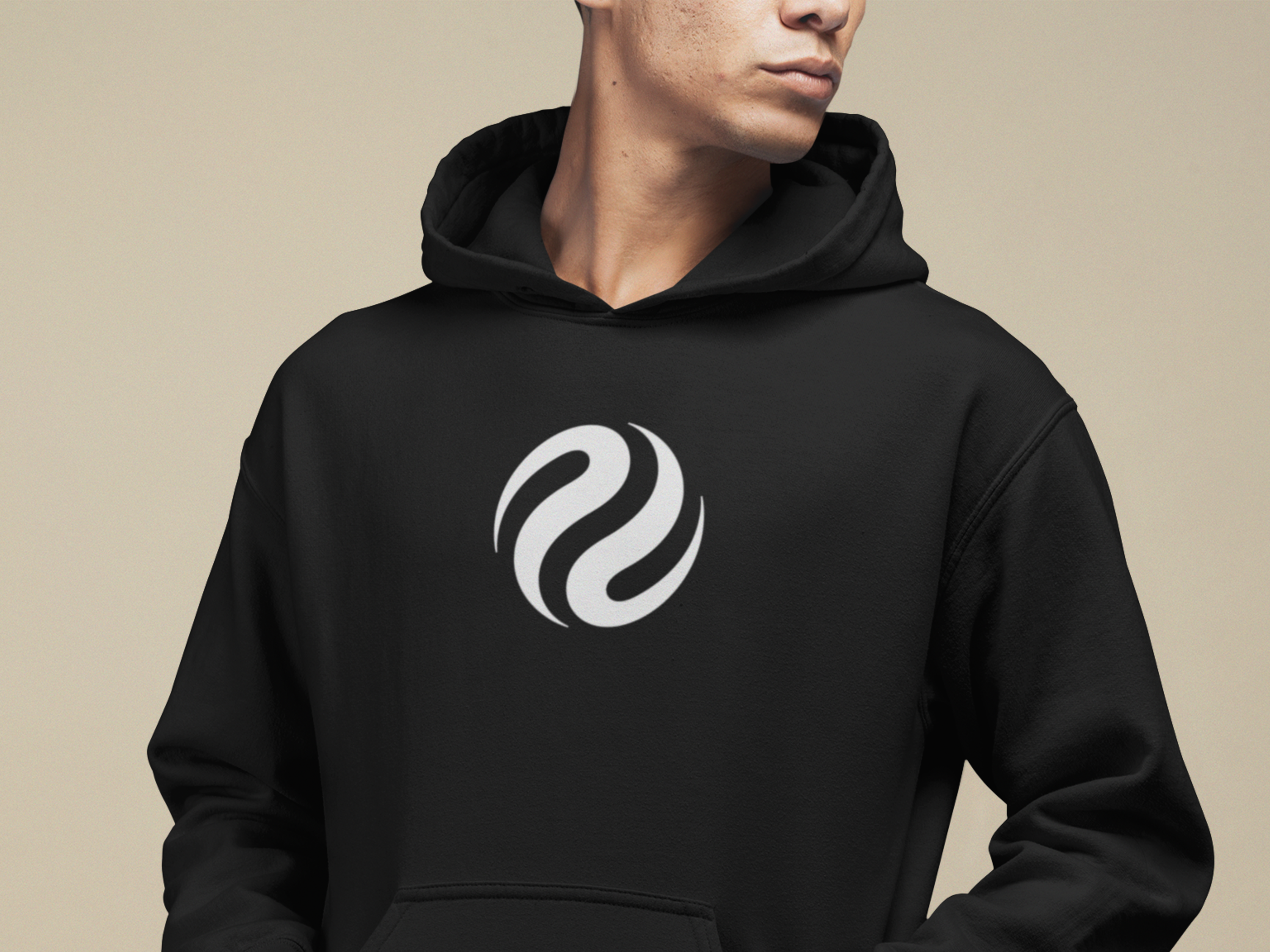 Person wearing a black hoodie with a white logo on a beige background