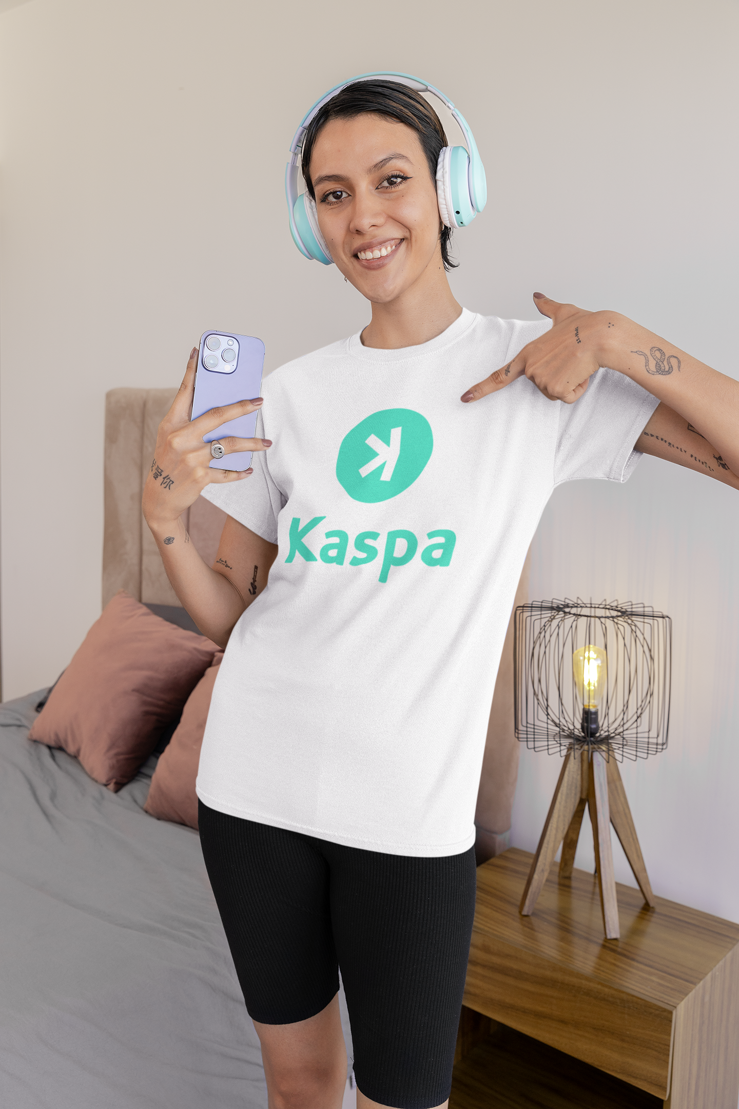 Person wearing a white t-shirt with Kaspa logo in a bedroom setting