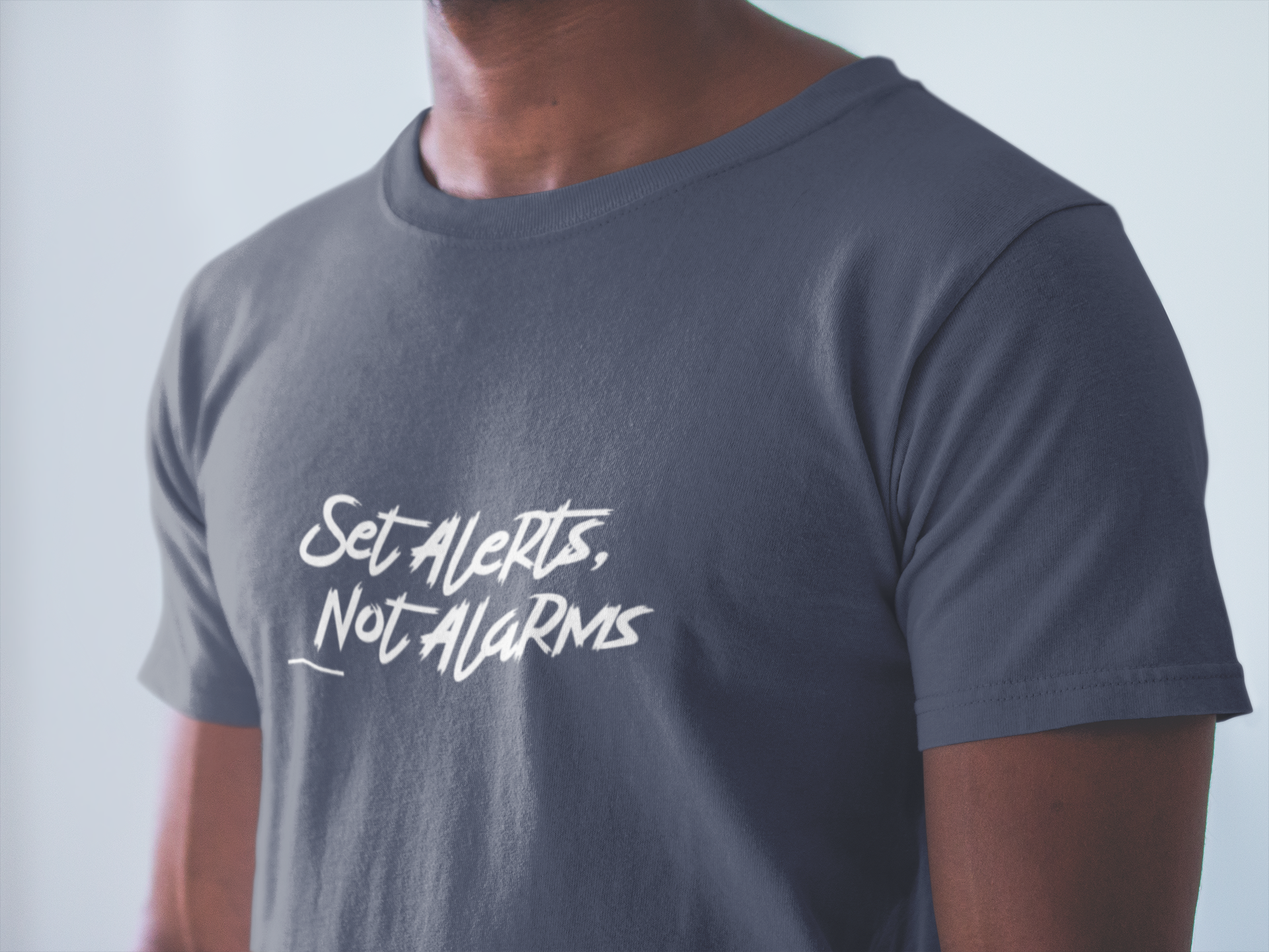 Person wearing a gray t-shirt with 'Set Alerts, Not Alarms' text.