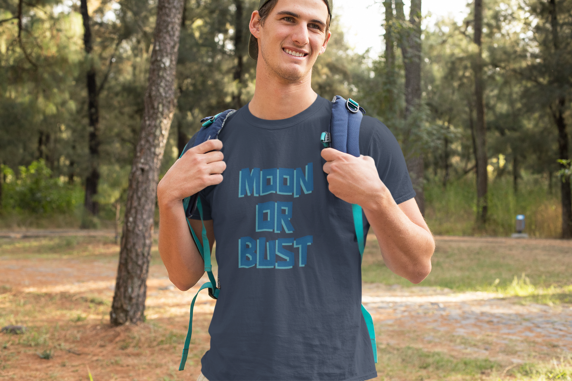 Man wearing a t-shirt with 'Moon or Bust' text in a forest setting