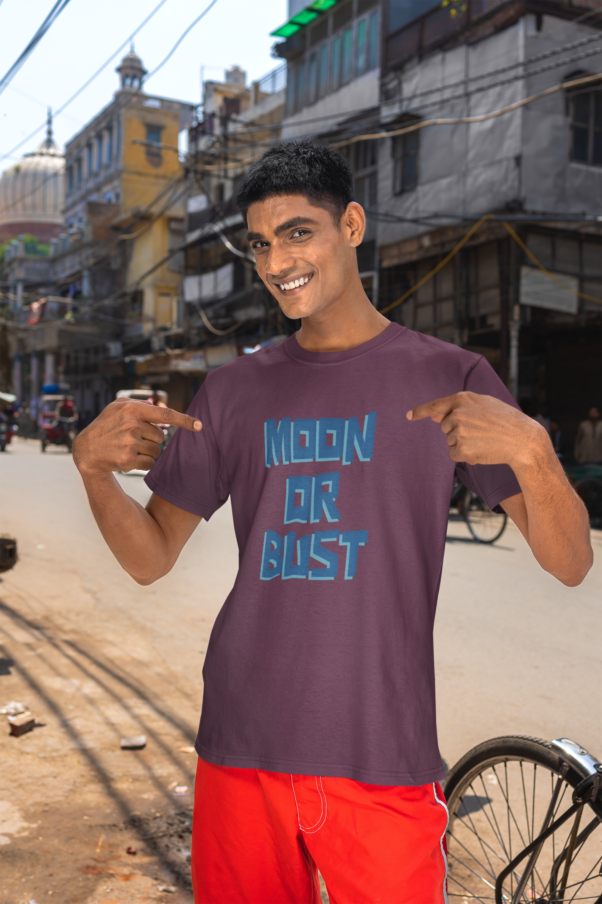 Man wearing a purple t-shirt with 'MOON OR BUST' text in an urban setting