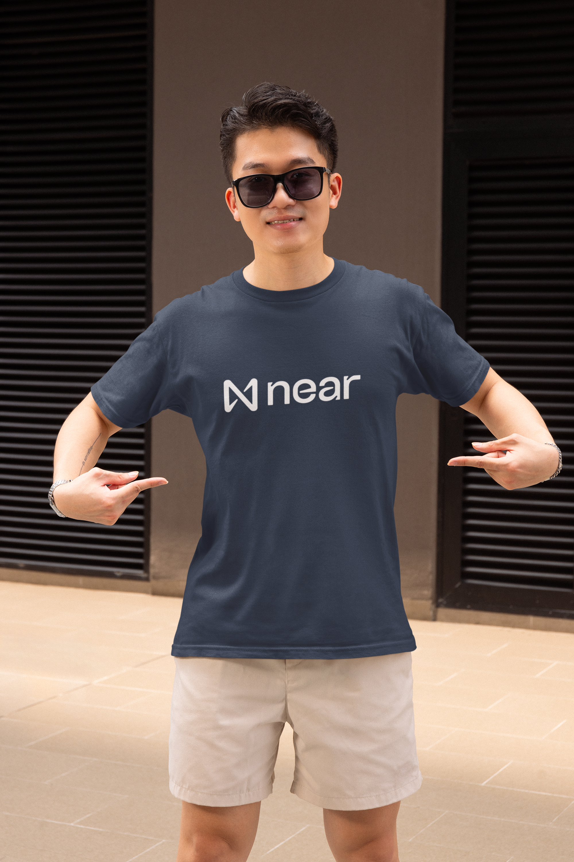 Person wearing a navy blue t-shirt with 'near' logo and sunglasses, posing against a dark background.