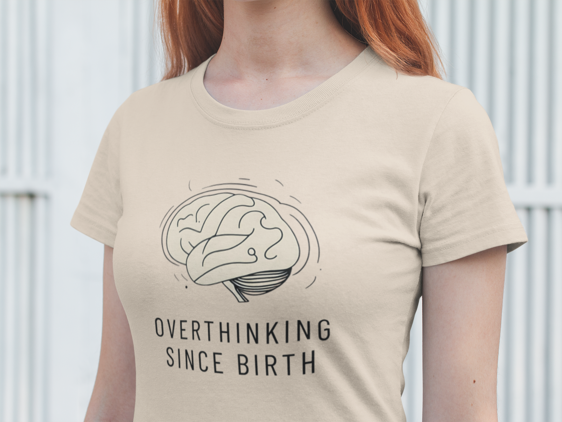 Woman wearing a beige t-shirt with a brain graphic and 'Overthinking Since Birth' text.