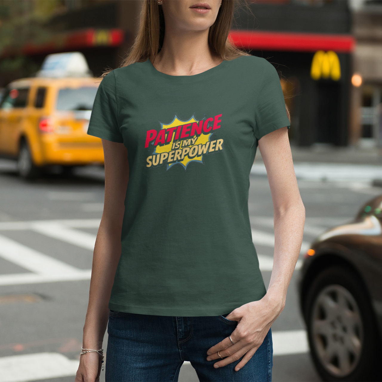 Person wearing a green t-shirt with 'Patience is a Superpower' text on a city street.