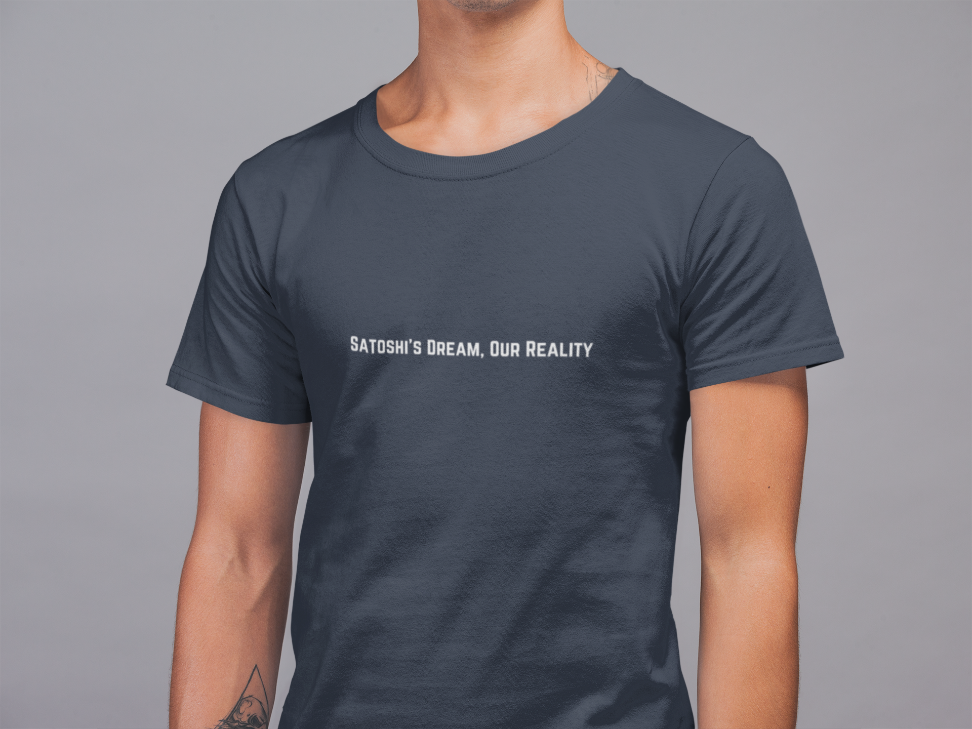 Person wearing a dark gray t-shirt with 'Satoshi's Dream, Our Reality' text on a gray background