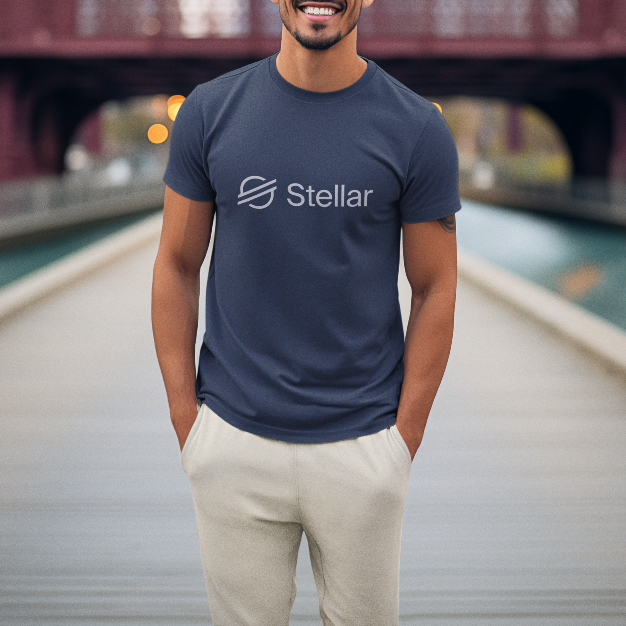 Man wearing a navy blue t-shirt with 'Stellar' logo on a dock with a bridge in the background