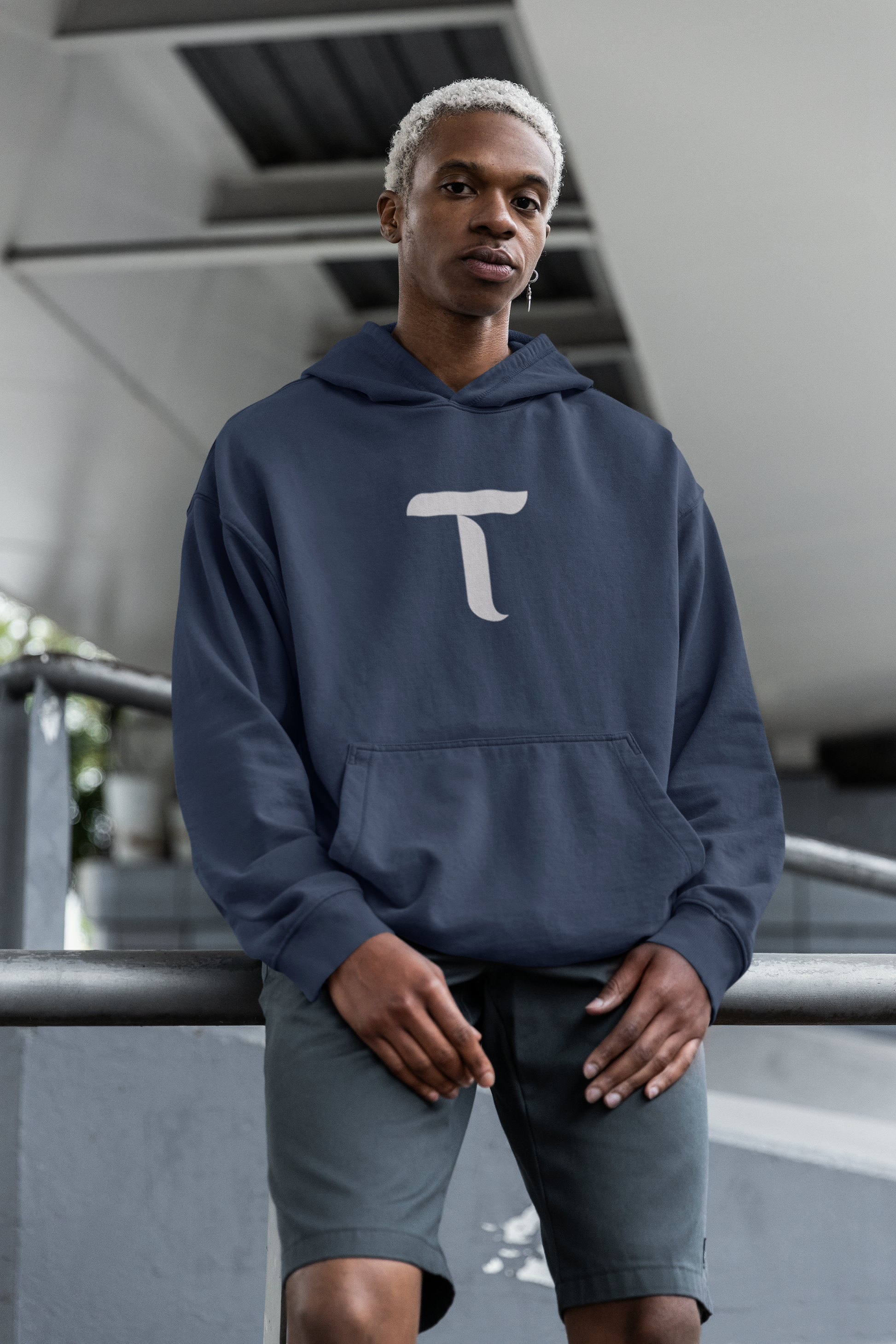Person wearing a navy blue hoodie with a white logo, standing indoors.