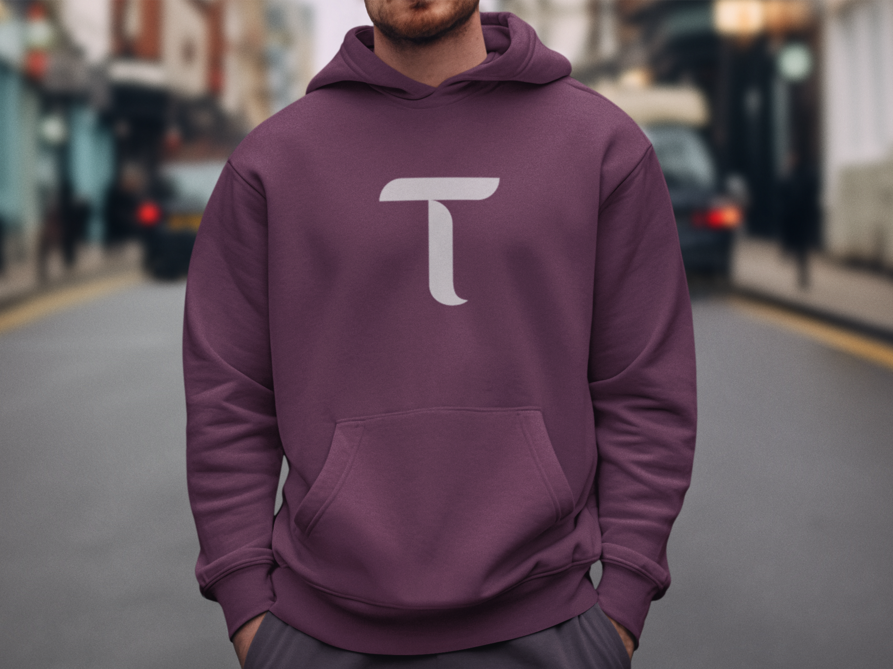 Person wearing a purple hoodie with a white logo on a street background