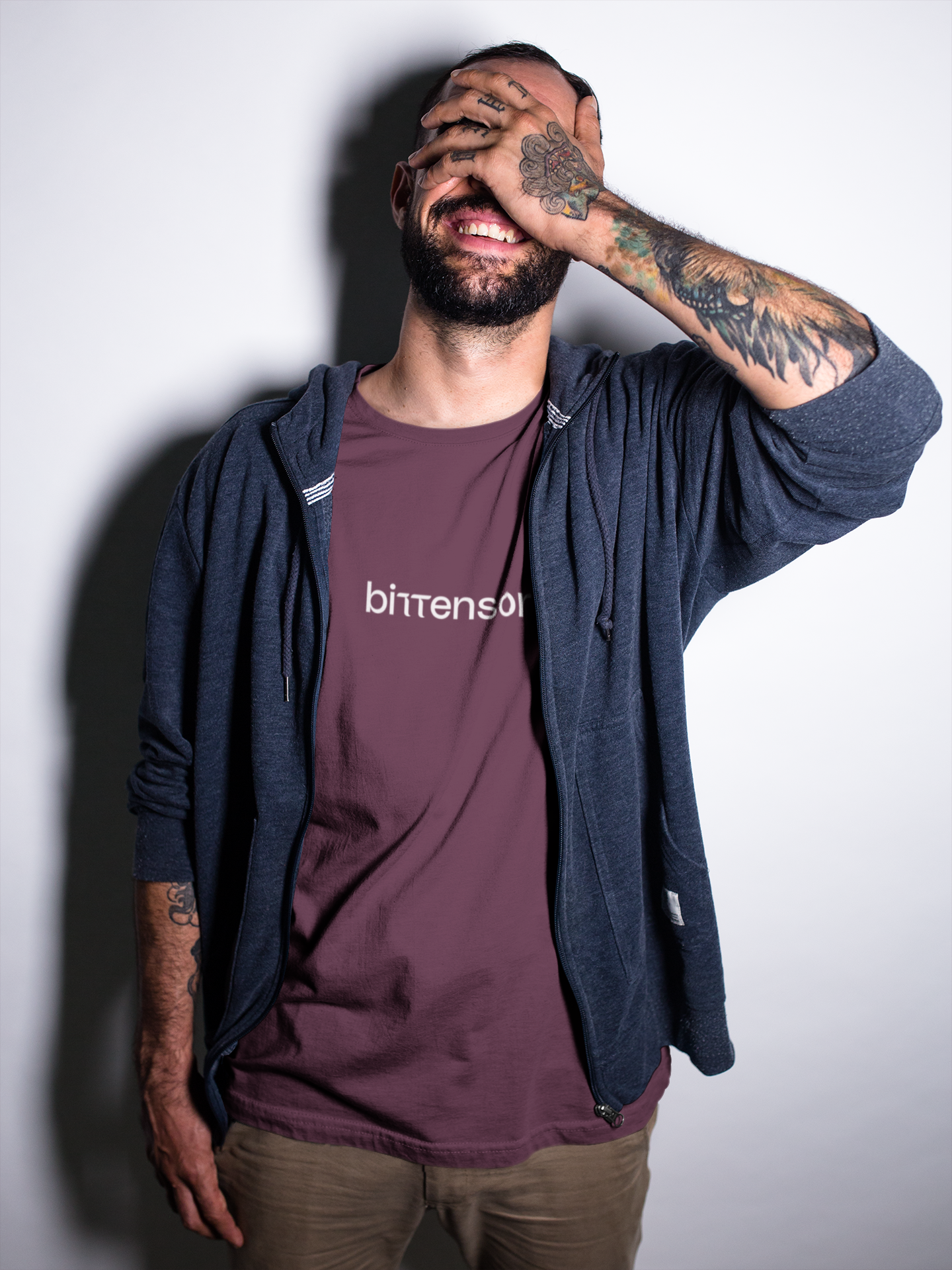 Man wearing a maroon t-shirt with 'bitten' logo and navy hoodie against a plain background