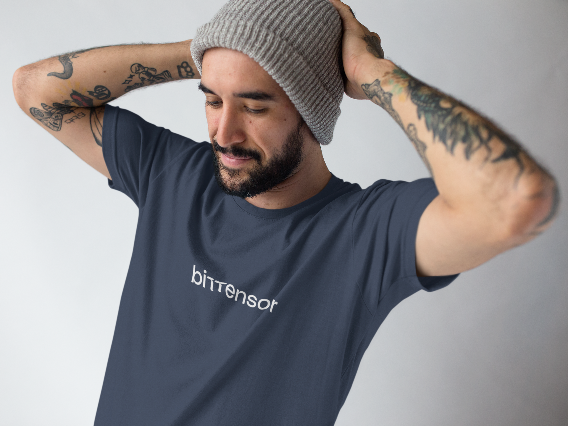 Man wearing a navy blue t-shirt with 'bittensor' logo and a gray beanie against a plain background