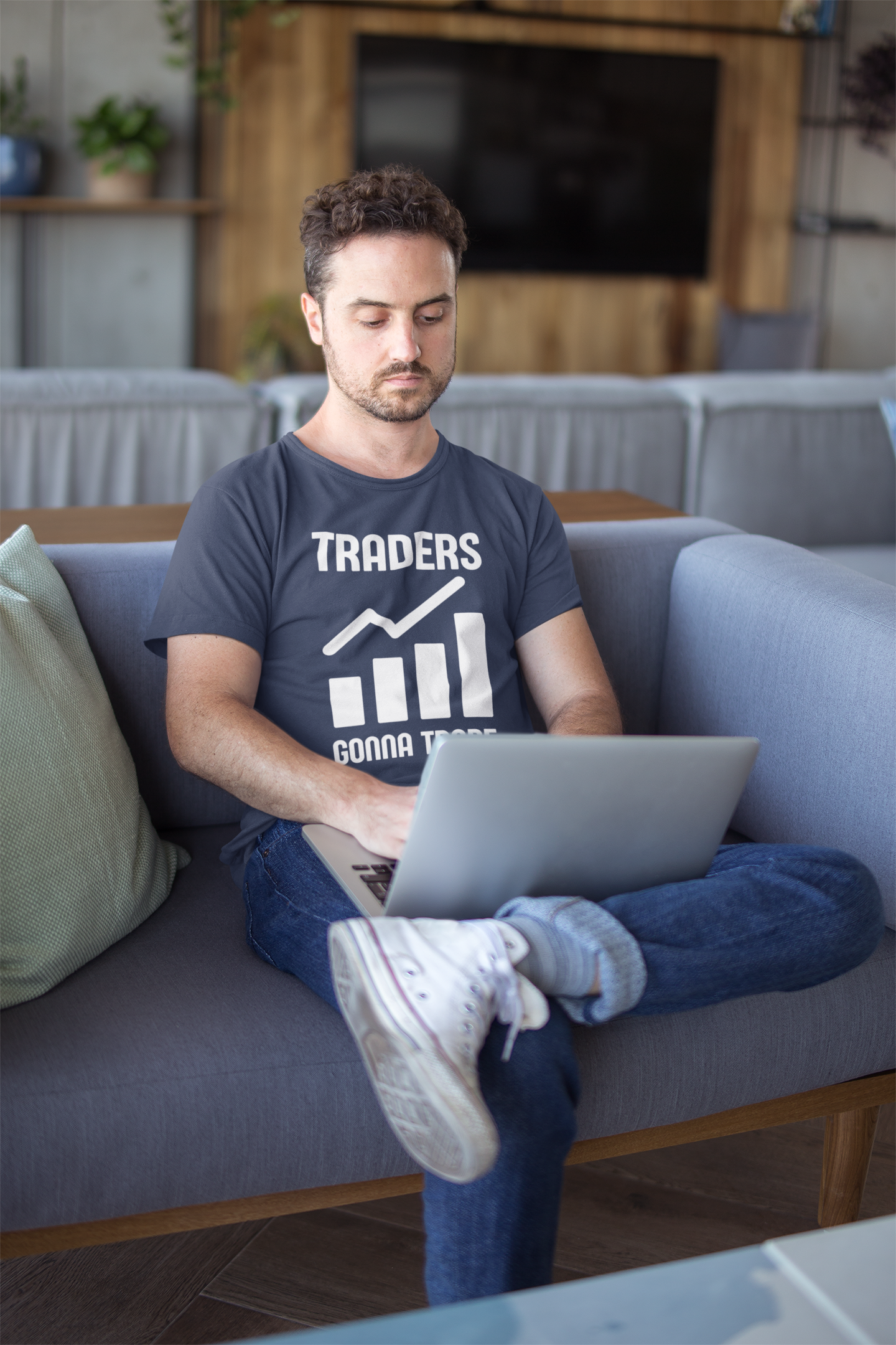 Man sitting on a couch using a laptop in a living room.