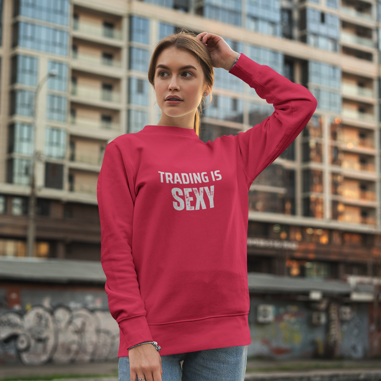 Person wearing a red sweatshirt with 'TRADING IS SEXY' text in an urban setting