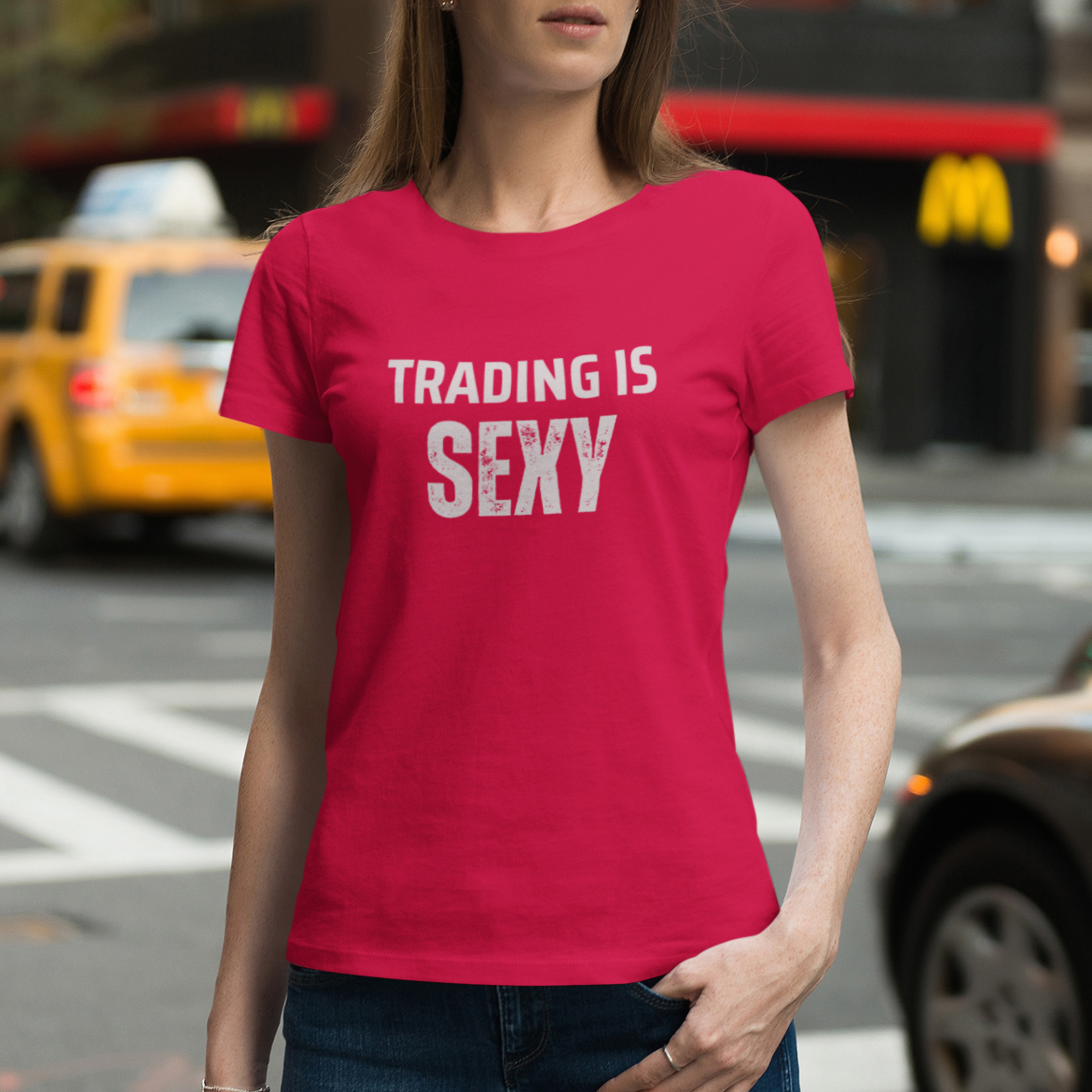 Woman wearing a red t-shirt with 'TRADING IS SEXY' text on a city street.