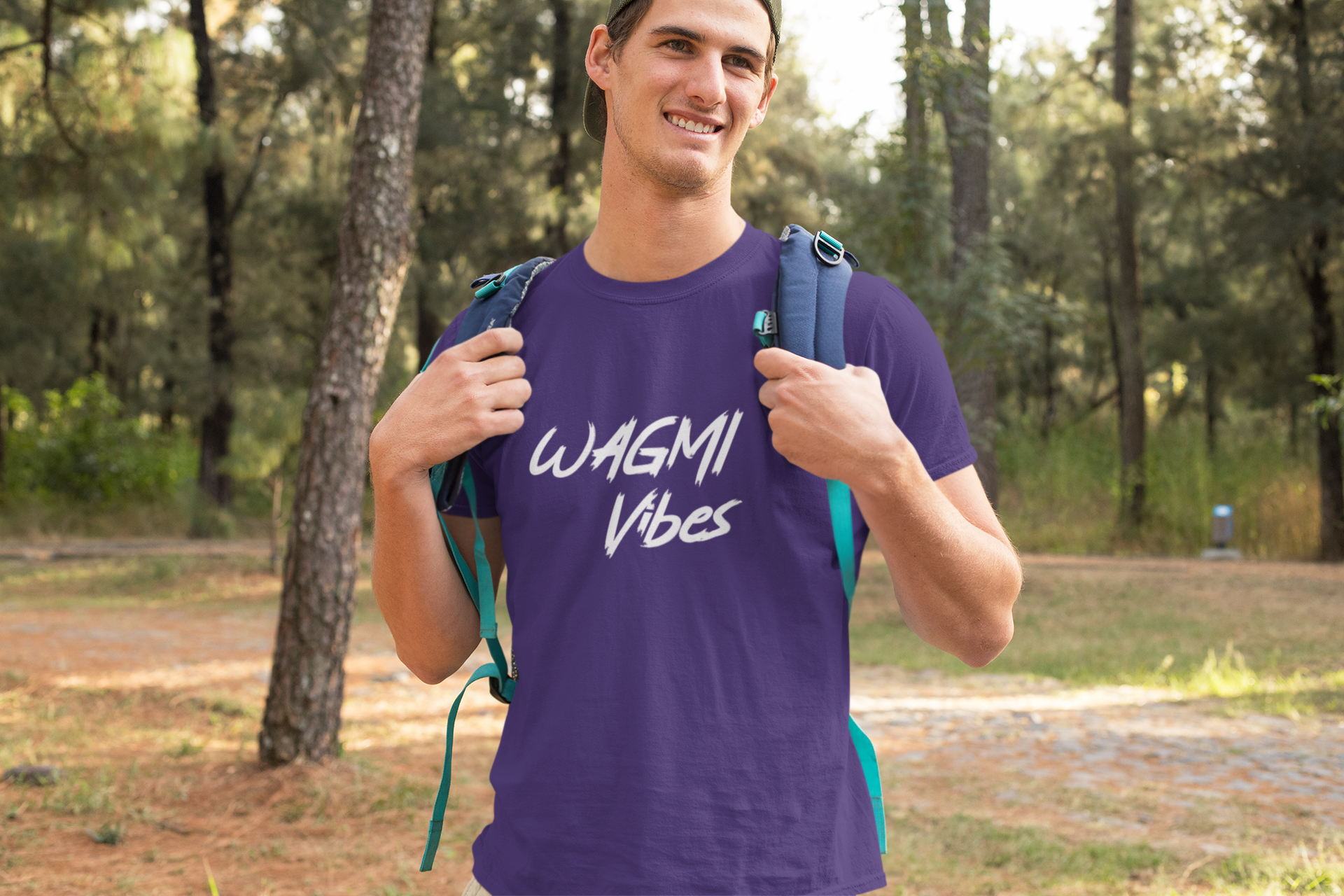 Man wearing a purple t-shirt with 'WAGMI Vibes' text, standing outdoors with trees in the background.