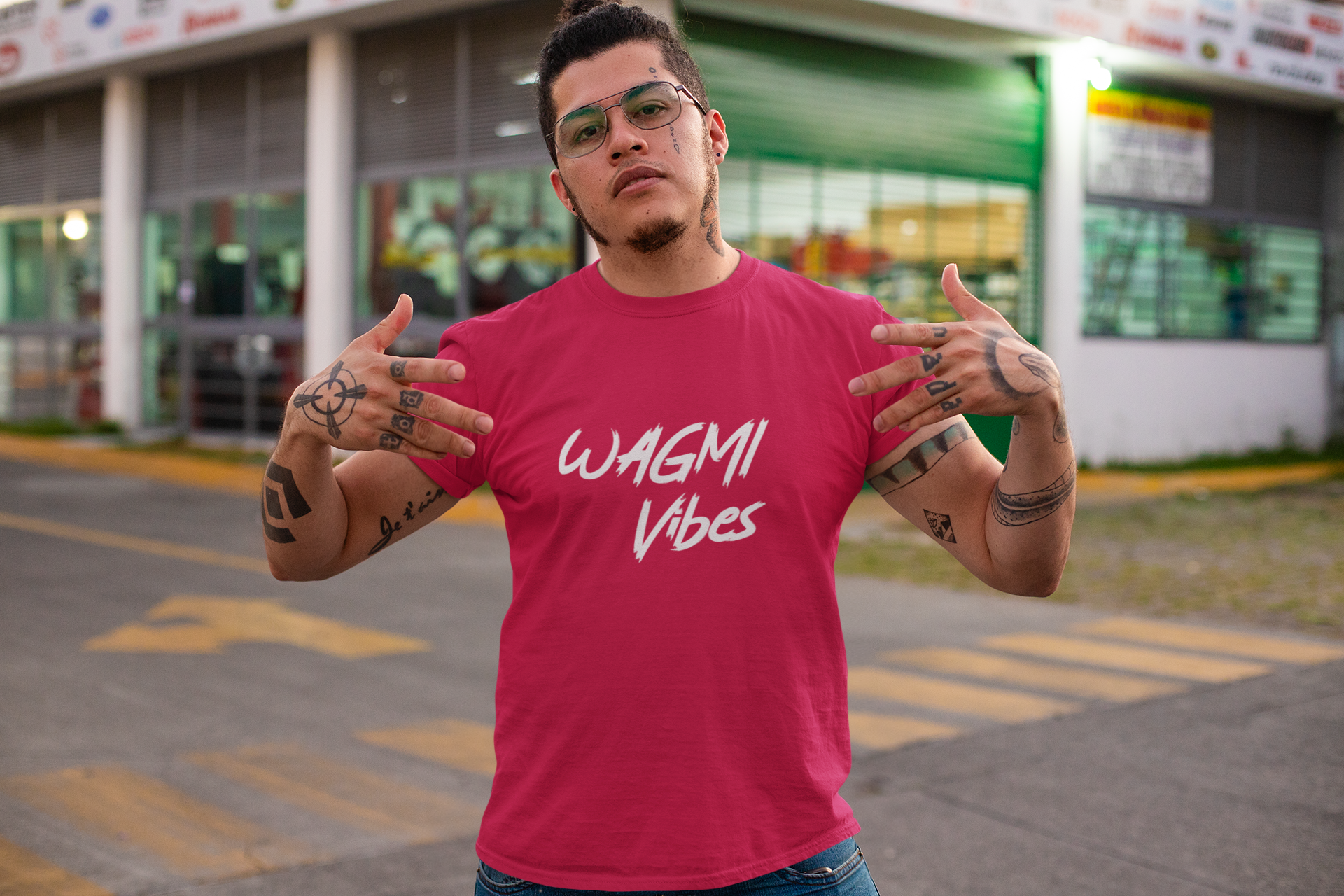 Man wearing a red t-shirt with 'WAGMI Vibes' text, standing in front of a store.