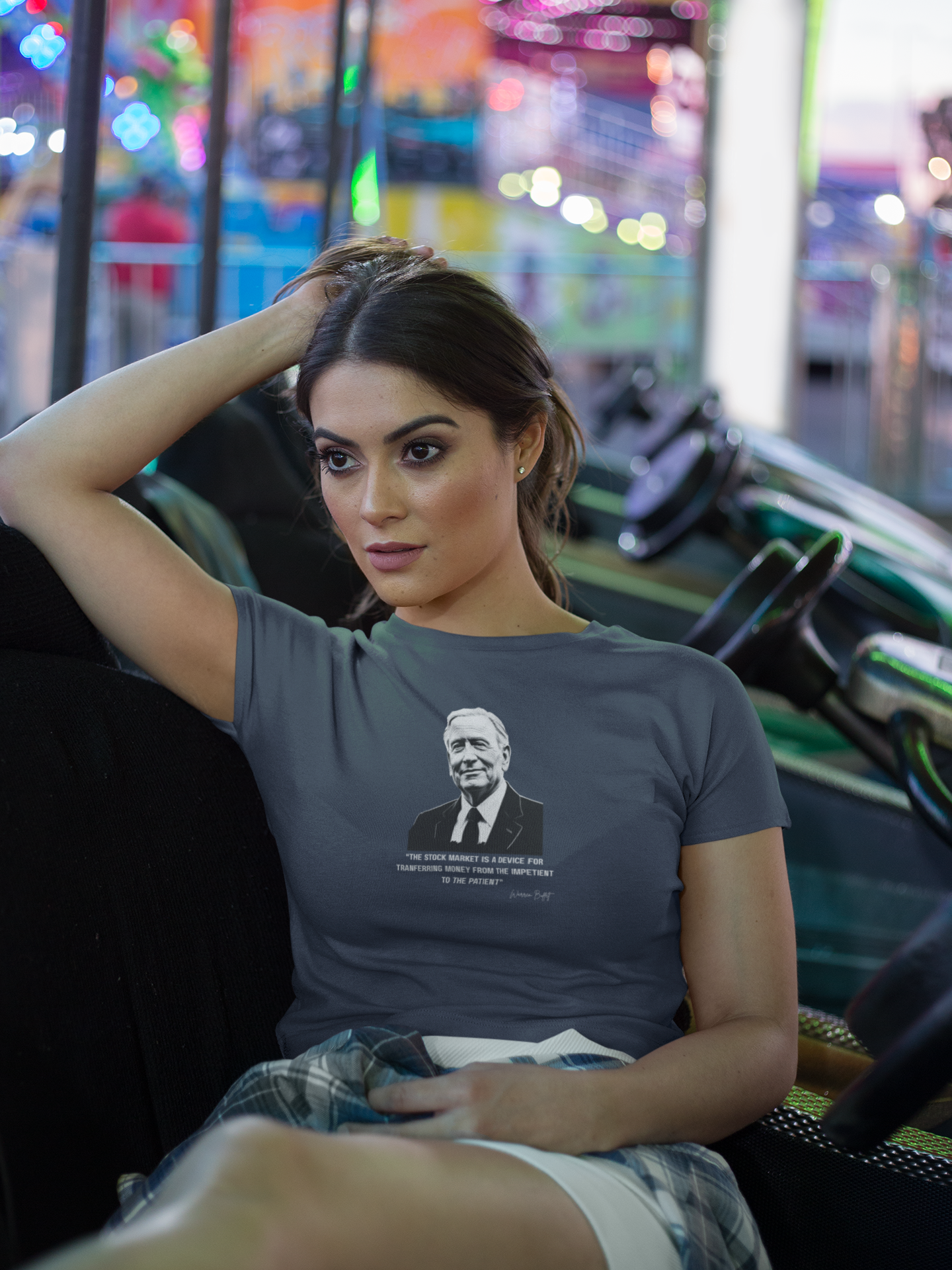 Woman sitting in a vehicle at an amusement park wearing a t-shirt with a graphic design.