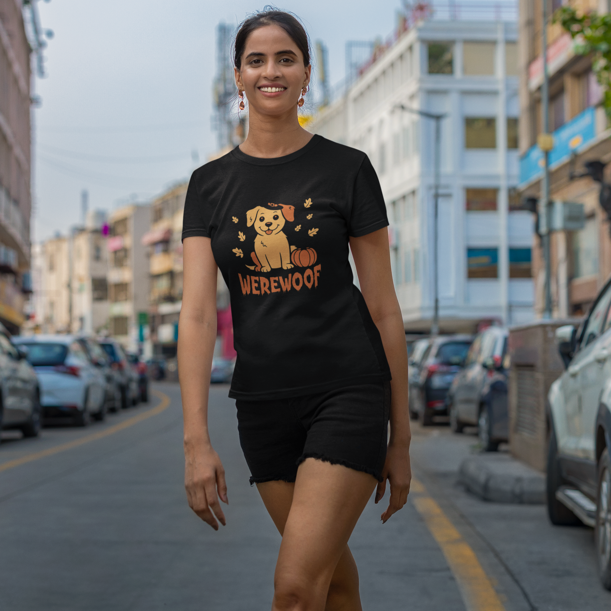 Woman wearing a black t-shirt with a graphic design and text, standing on a street.