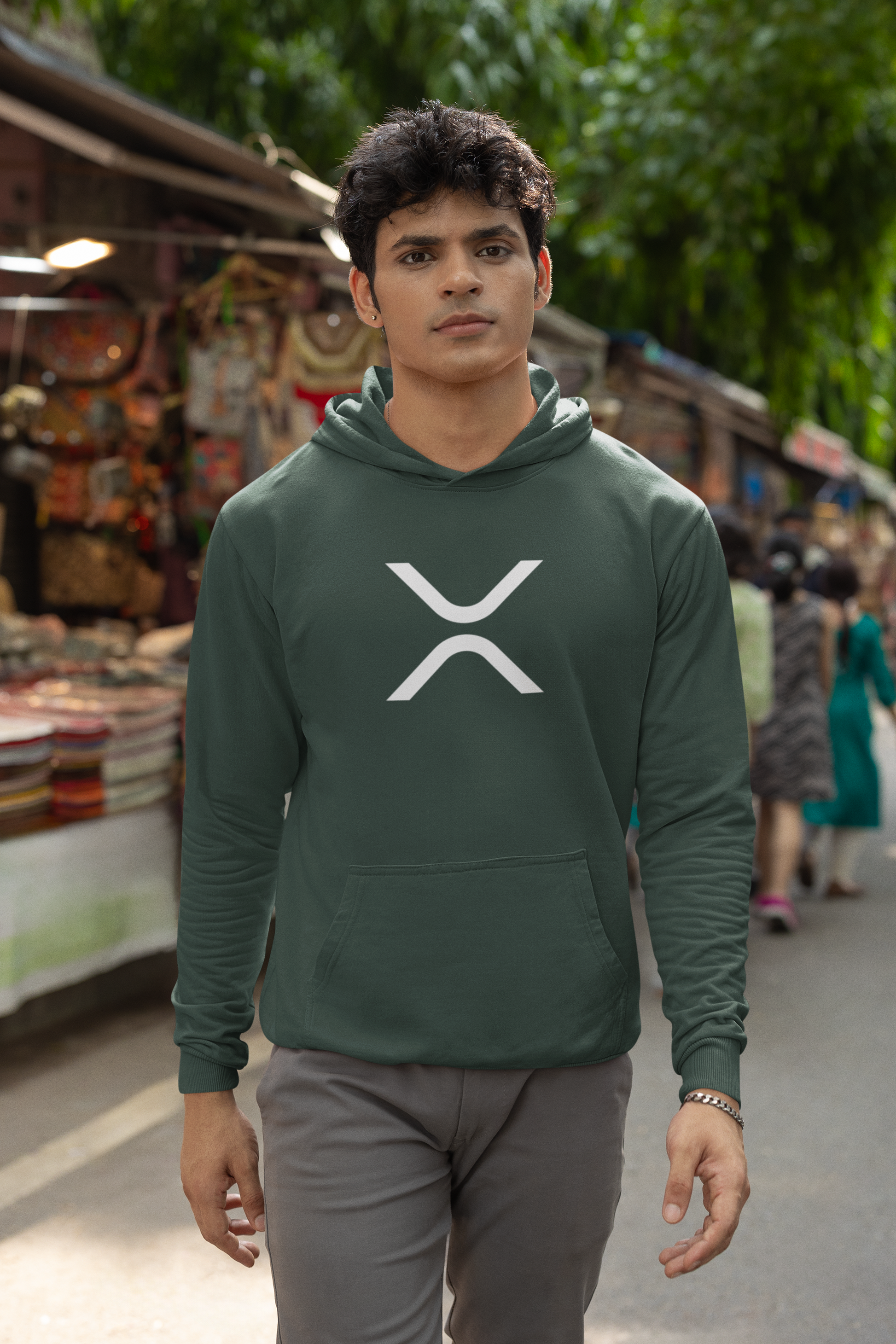 Man wearing a green hoodie with a logo in an outdoor setting